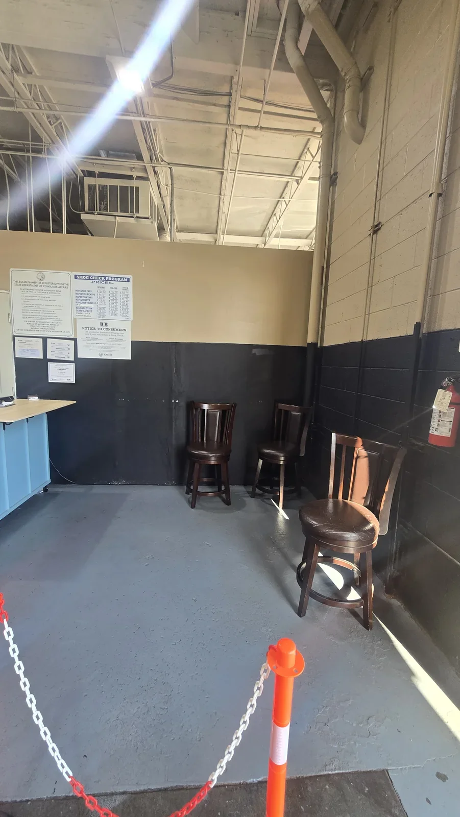 OC Smog Lab customer waiting area with three chairs and posted smog-check information