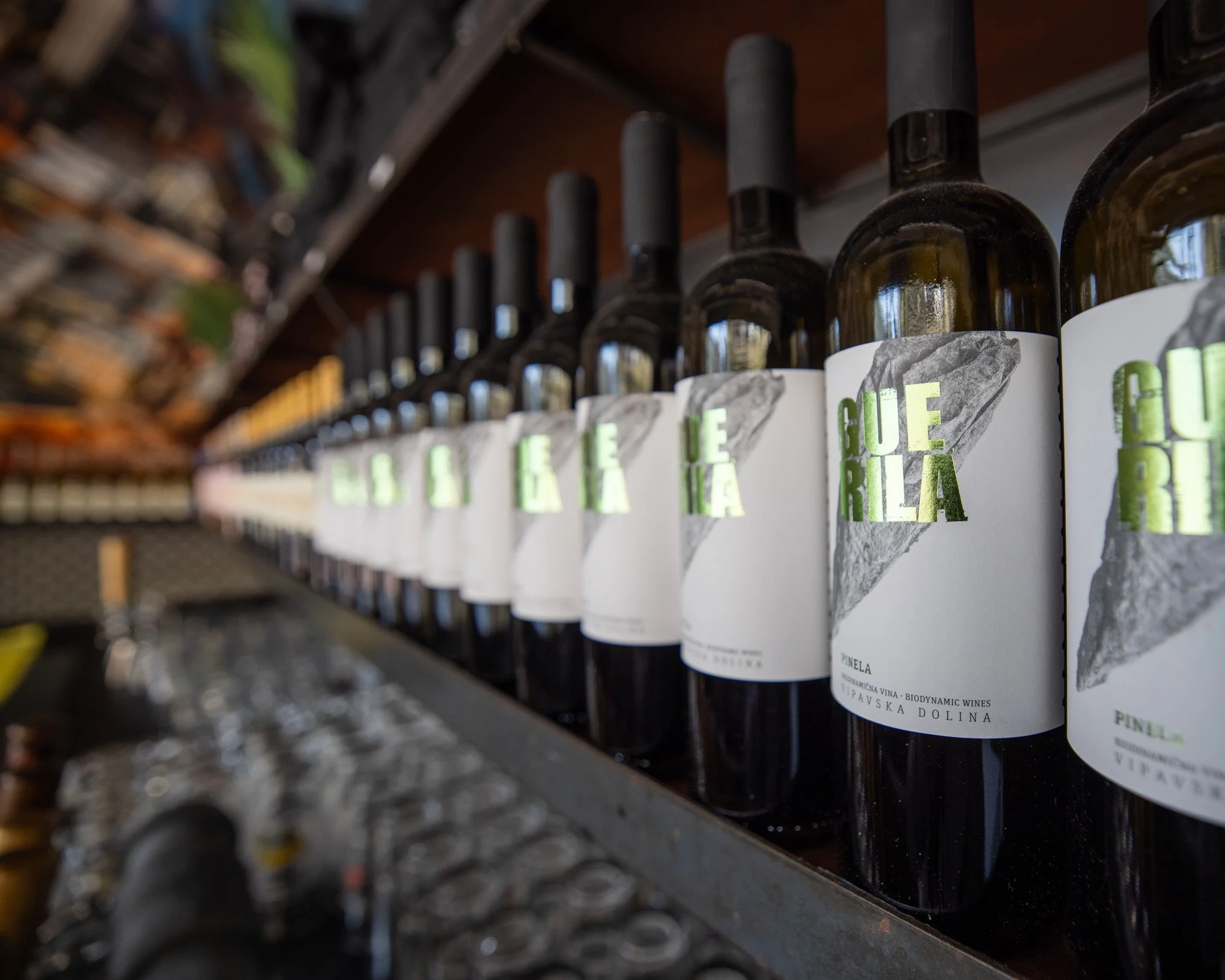 A row of wine bottles on a store shelf with visible labels that read 'GUE' and 'RELIA'.