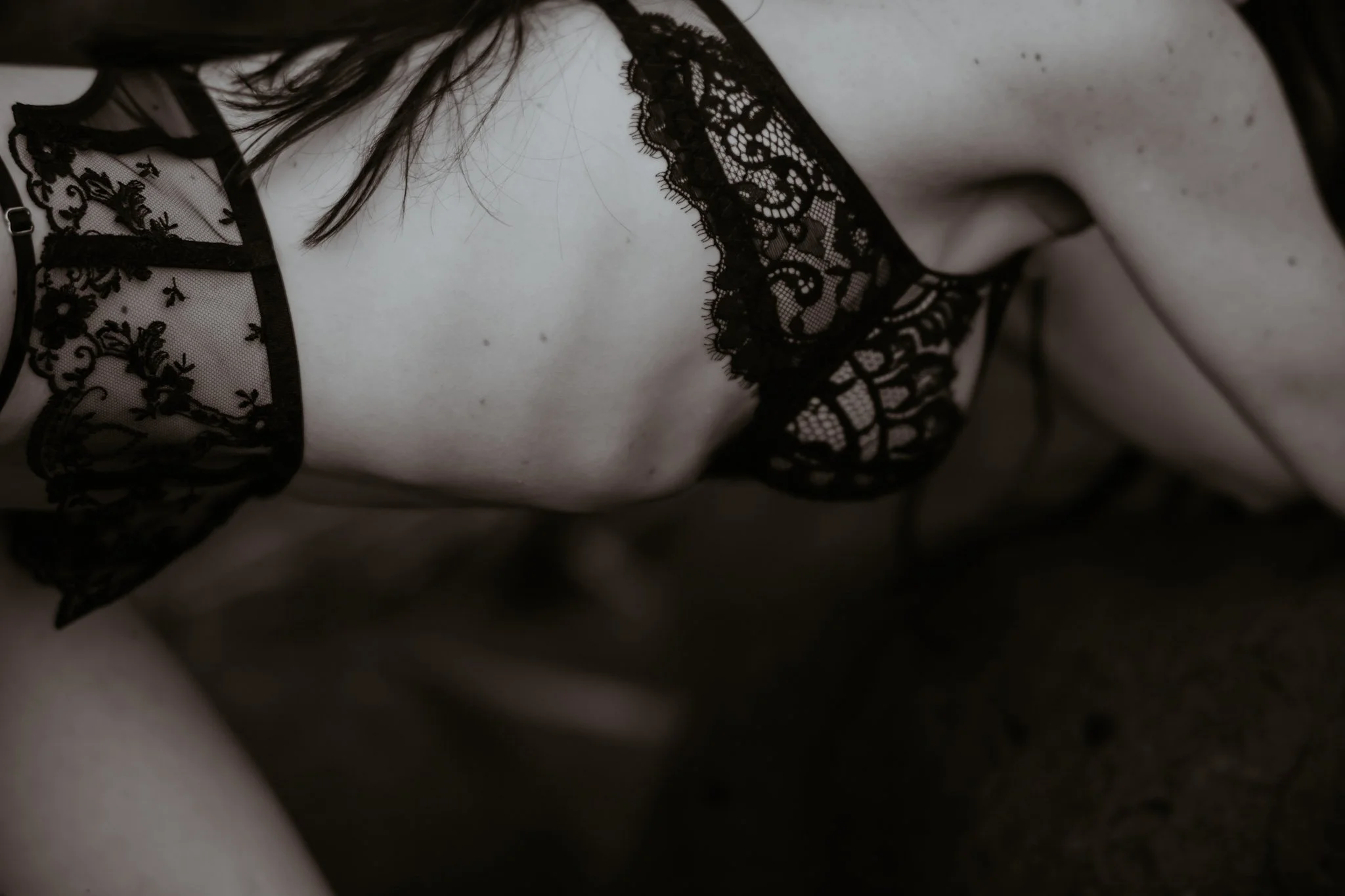 Close-up of a person's torso wearing black lace lingerie with floral patterns.