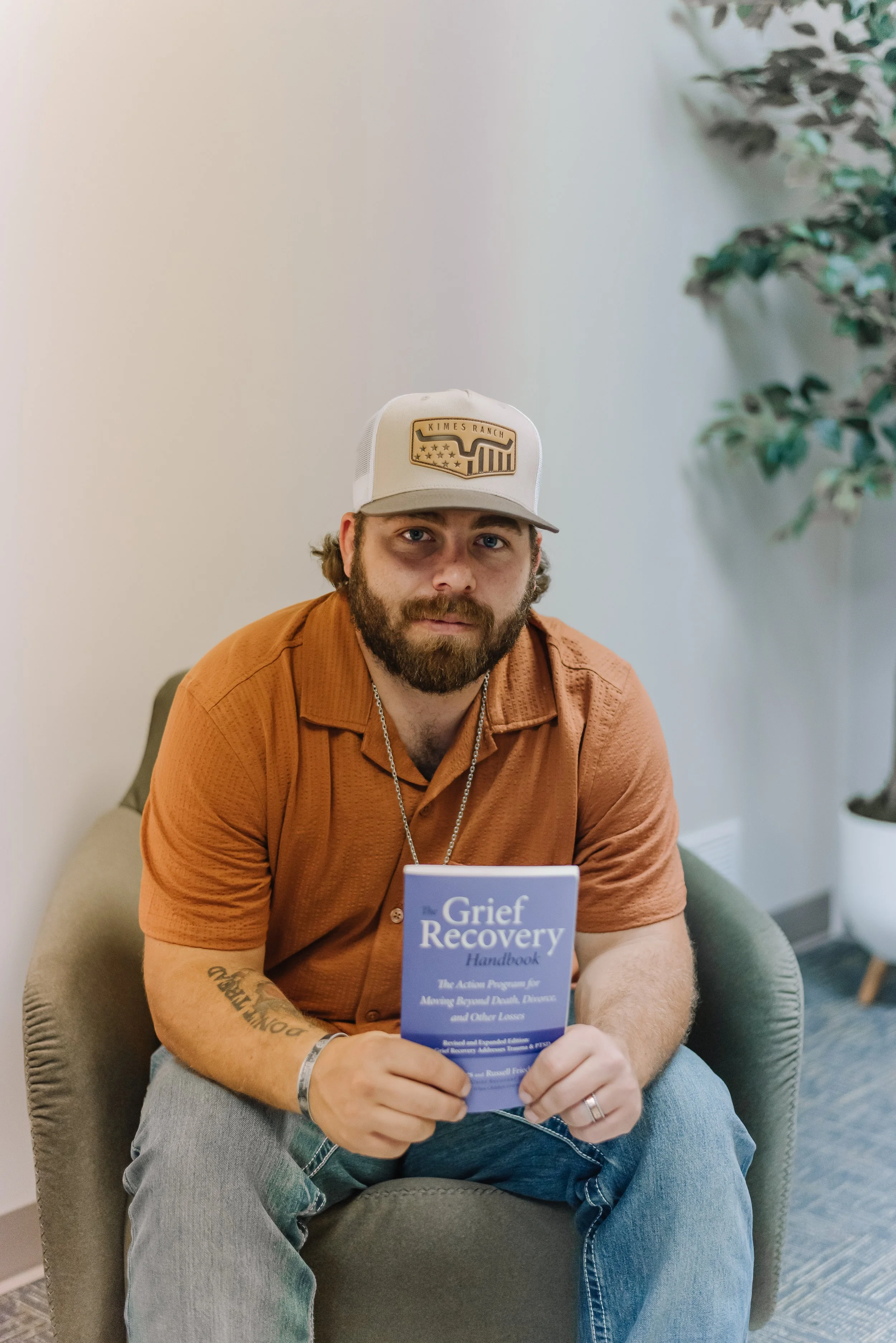 Coach holding a grief recovery handbook during a support session at Bond Grief Collective in Manhattan, KS.