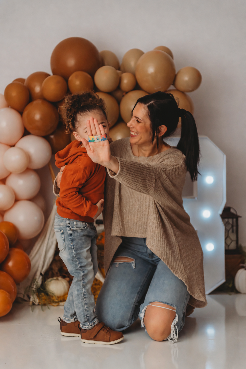 A woman and a young child sharing a joyful moment, with a balloon display in the background.