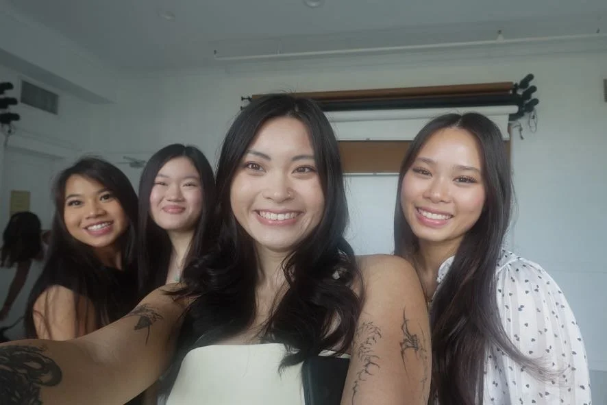Four young women smiling and taking a selfie in a photography studio.