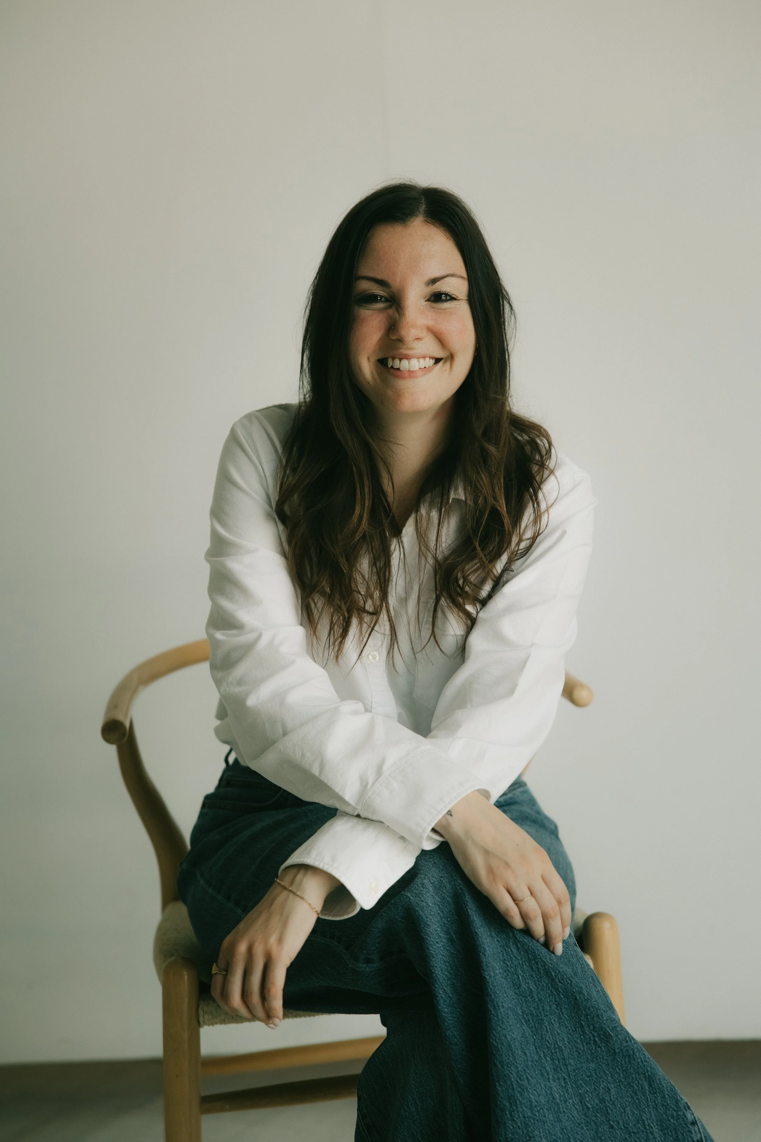 Rachael Ashcraft, Individual & Couples Therapist in Austin, TX in wooden chair & neutral background
