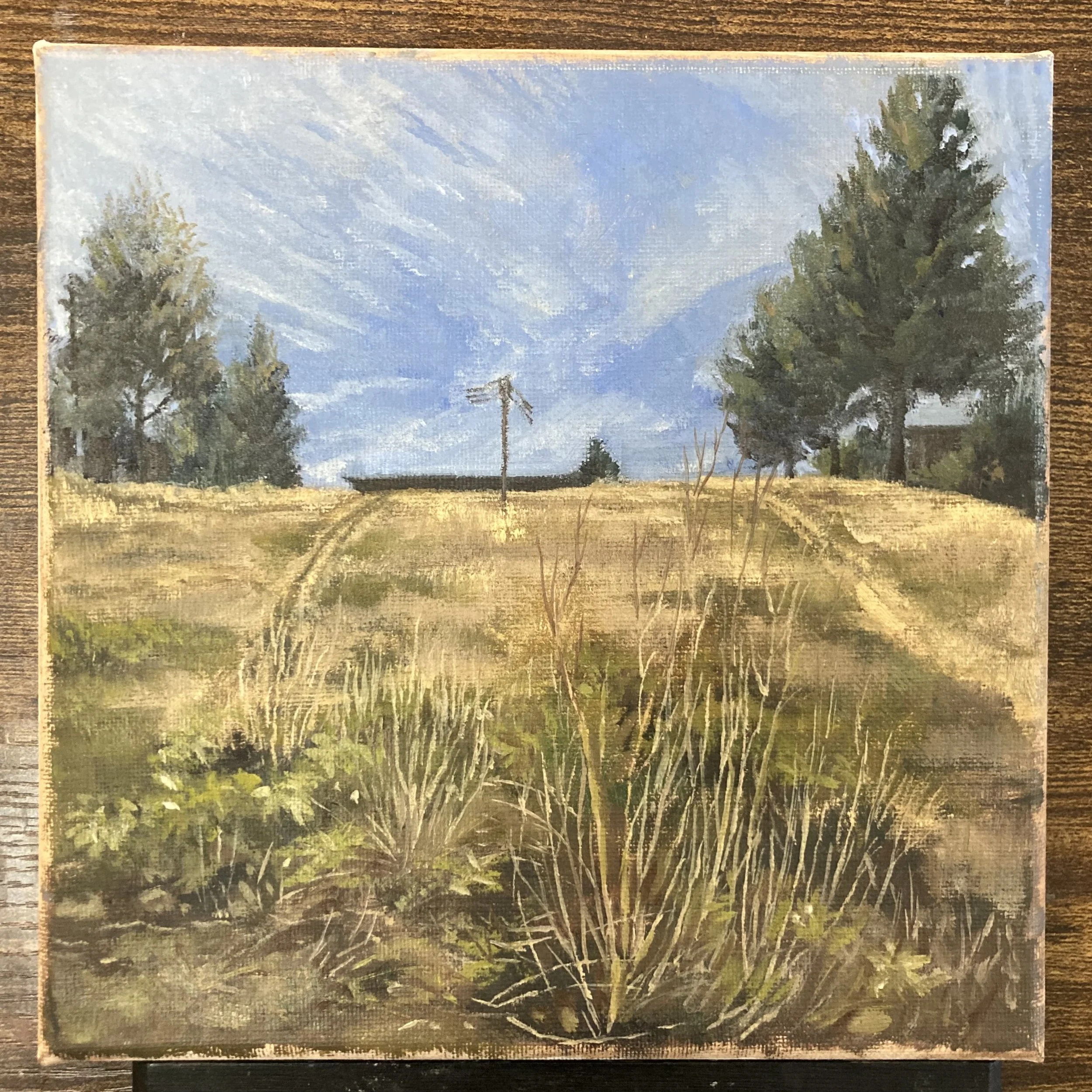 A landscape painting of a field with grass and trees under a blue sky with wispy clouds.