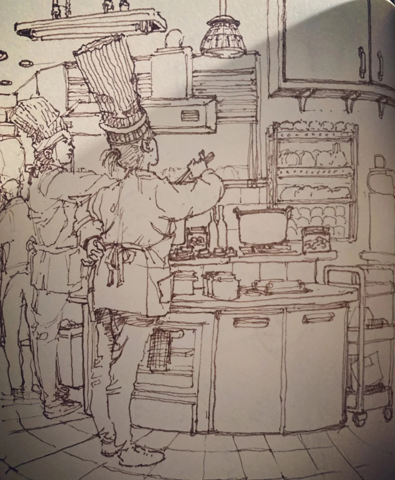 Sketch of a person in a kitchen, drawing or writing at a counter surrounded by kitchen appliances and shelves.