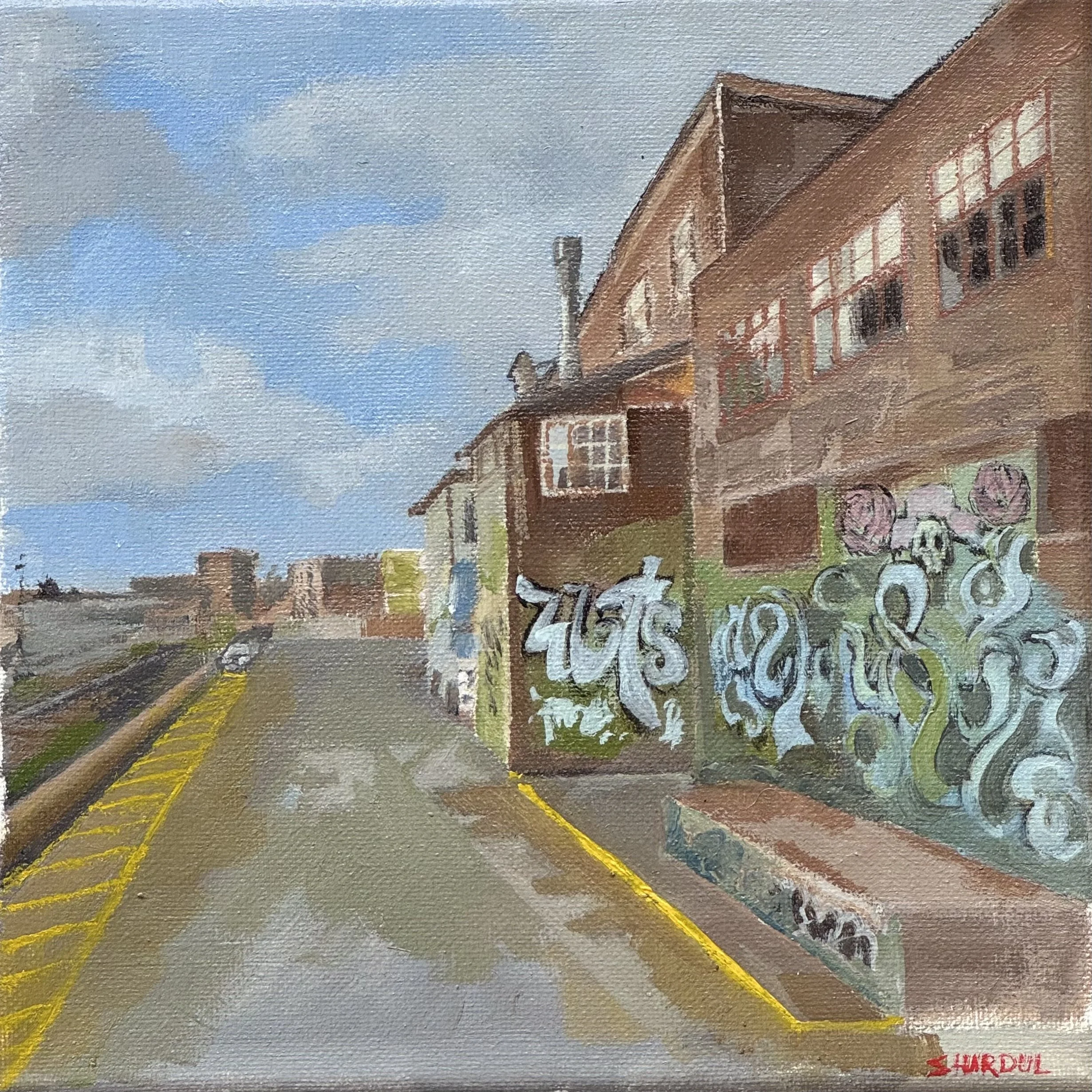 A painting depicting a street scene with buildings, a partly cloudy sky, and a road with yellow lines, with some trees and graffiti on a wall in the foreground.