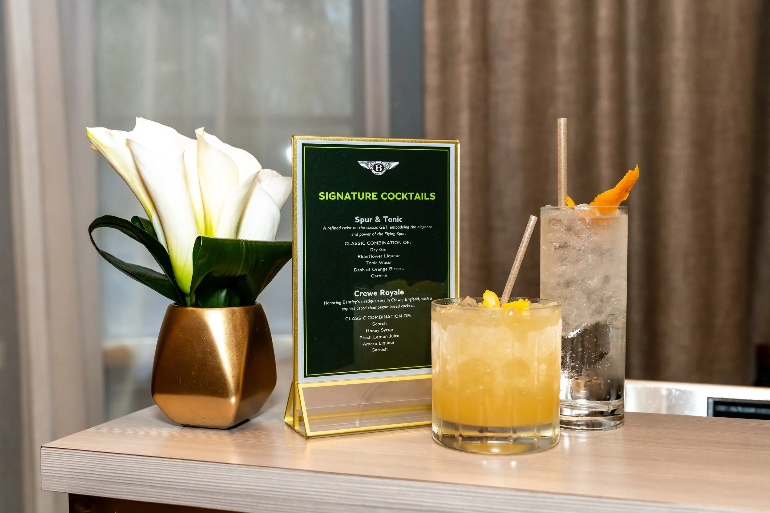 a picture of a signature cocktail menu with Bentley branding and floral scape