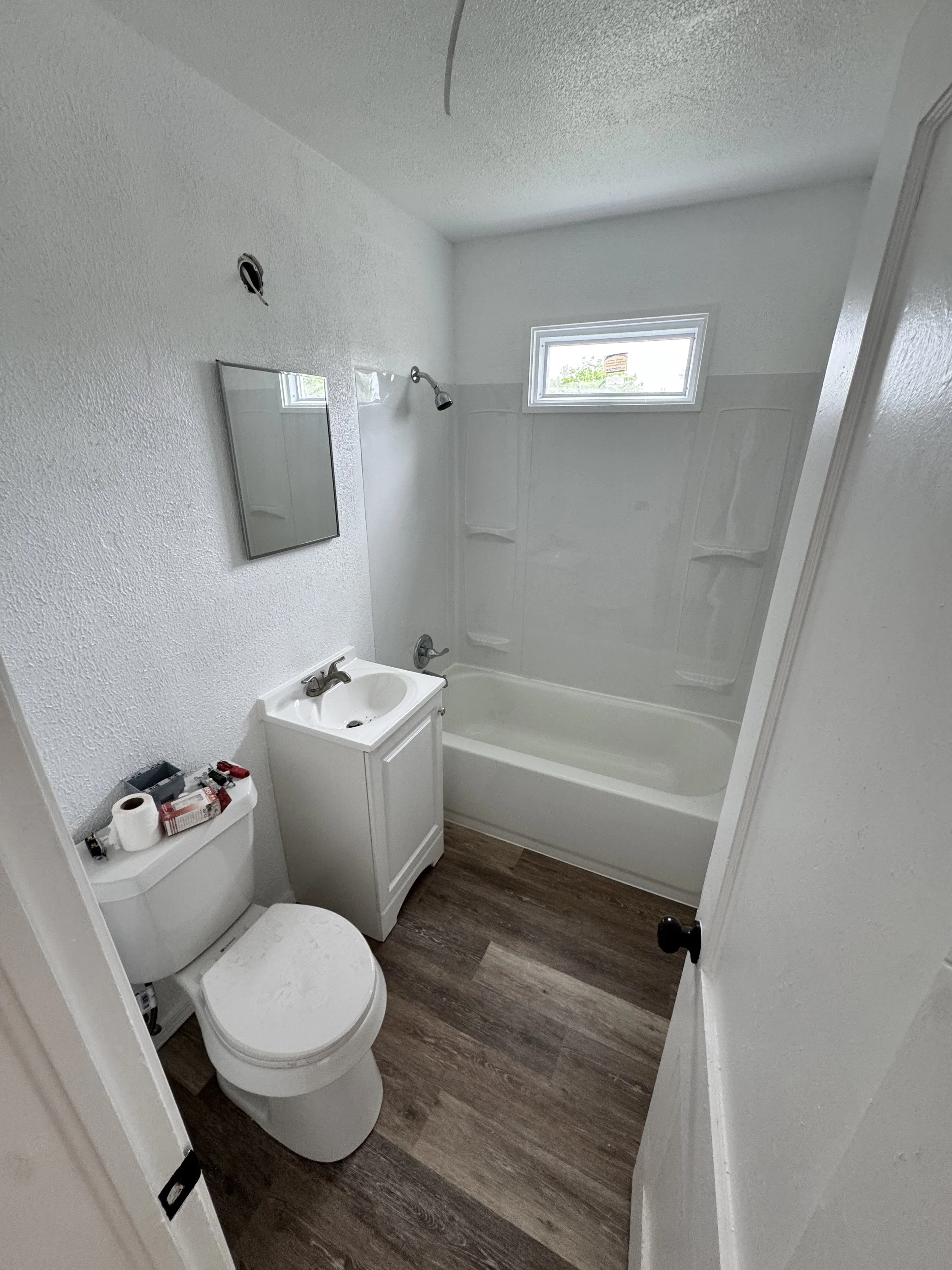 bathroom remodel in Oklahoma City, OK tub with white surround, white vanity, toilet installation, vinyl plank flooring installation.