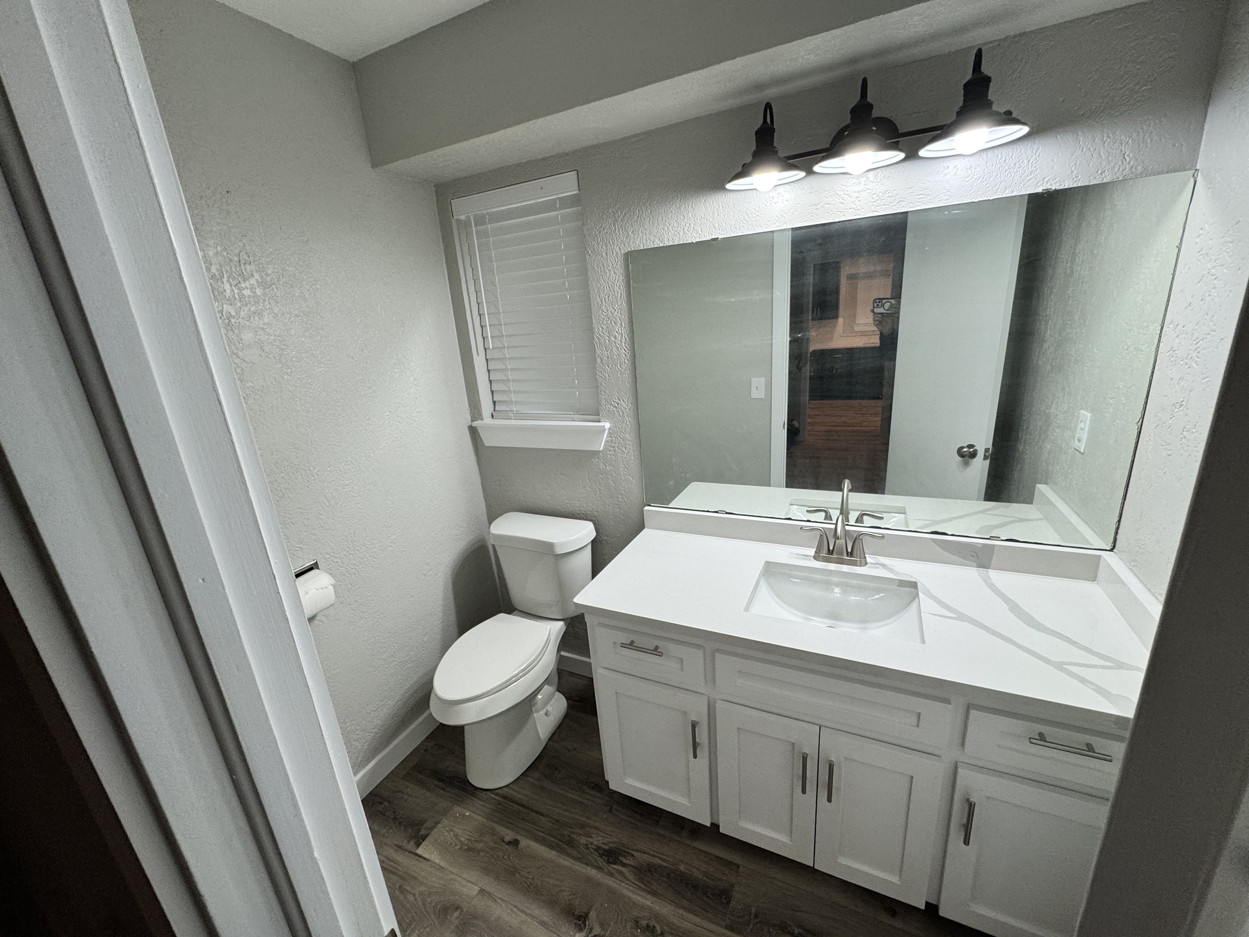 bathroom remodel in Choctaw, OK. Cabinet vanity painting, white quartz countertops, toilt install, vinyl plank flooring