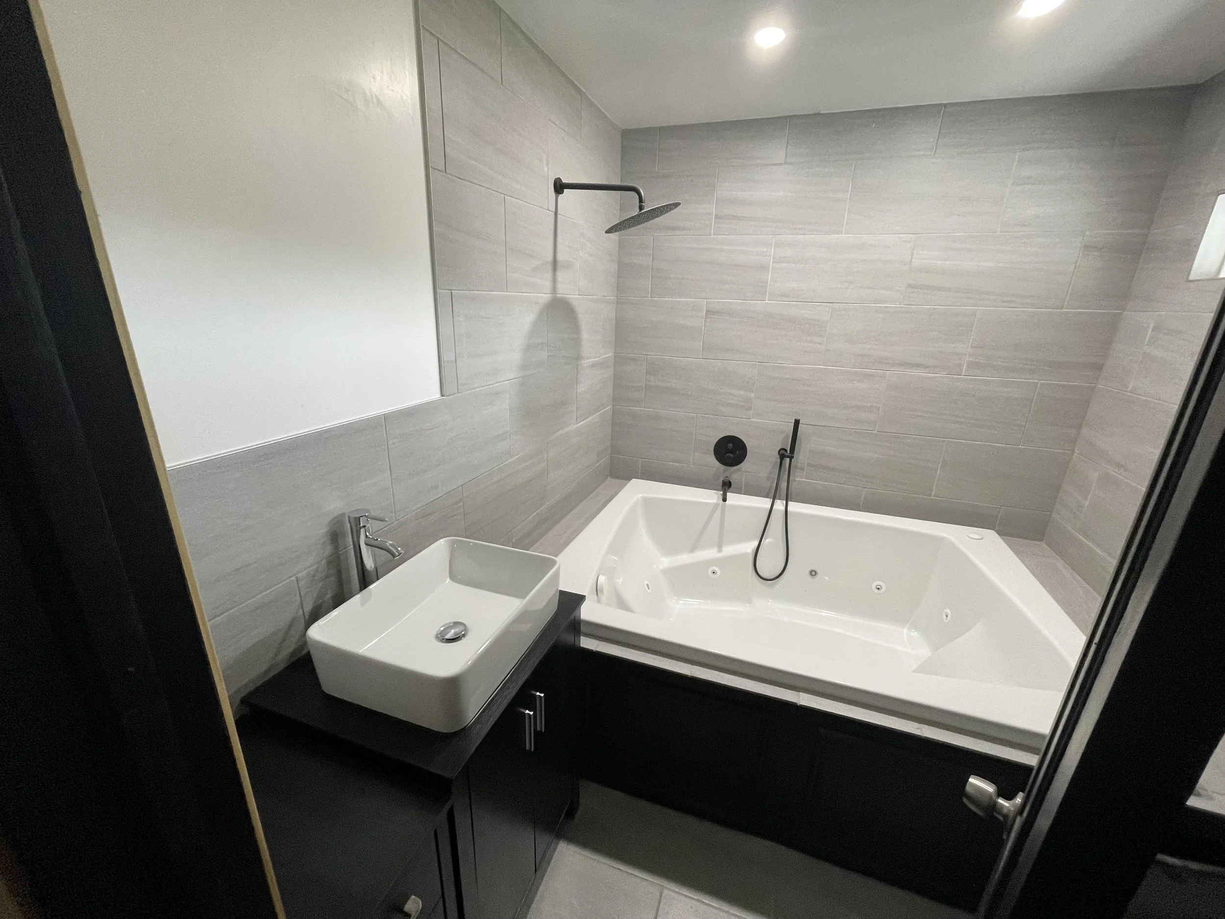 bathroom remodel in Midwest City, OK oversized jacuzzi tub, black vanity with white sink, custom tiles shower surround, interior painting.