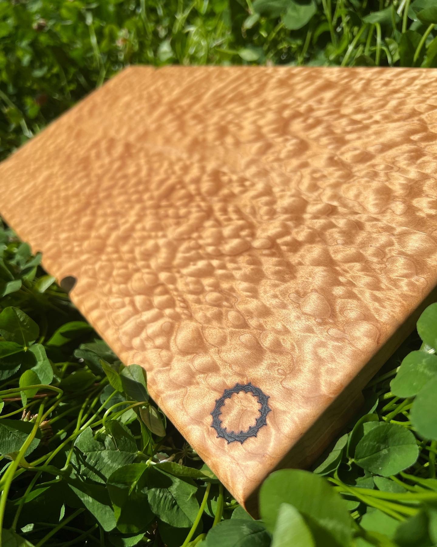 Maple cutting board with a curly grain pattern and the Kingdom Kraft logo permanently branded onto the corner