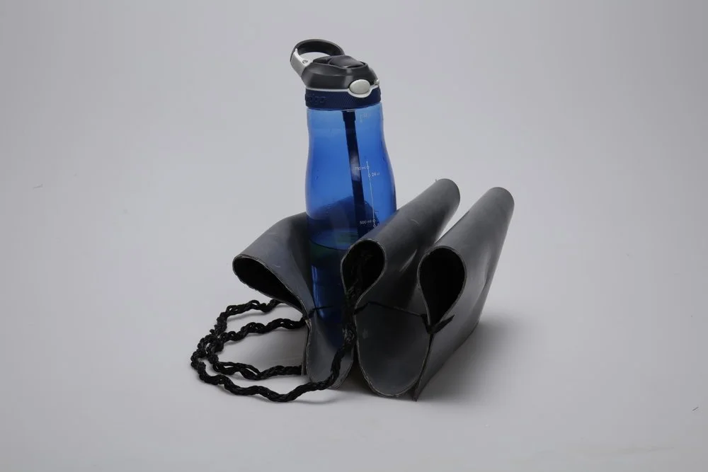 A blue water bottle, black bag, and black gloves on a gray background.