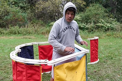 Young man in a gray hoodie inside a cardboard roller coaster prop outdoors
