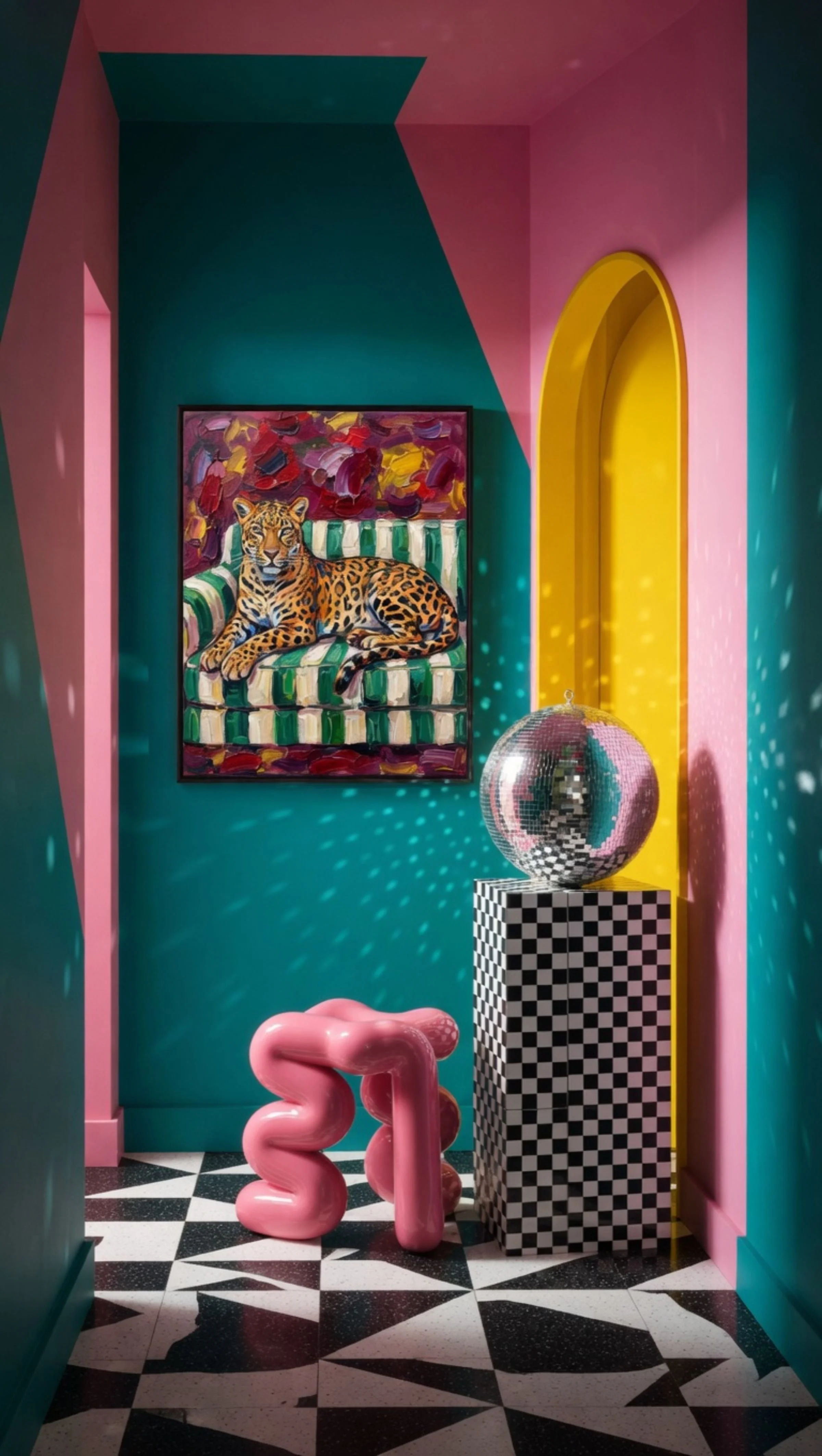 Colorful room with geometric decor, a painting of a leopard on a striped sofa, a disco ball on a checkered pedestal, and abstract-shaped furniture.