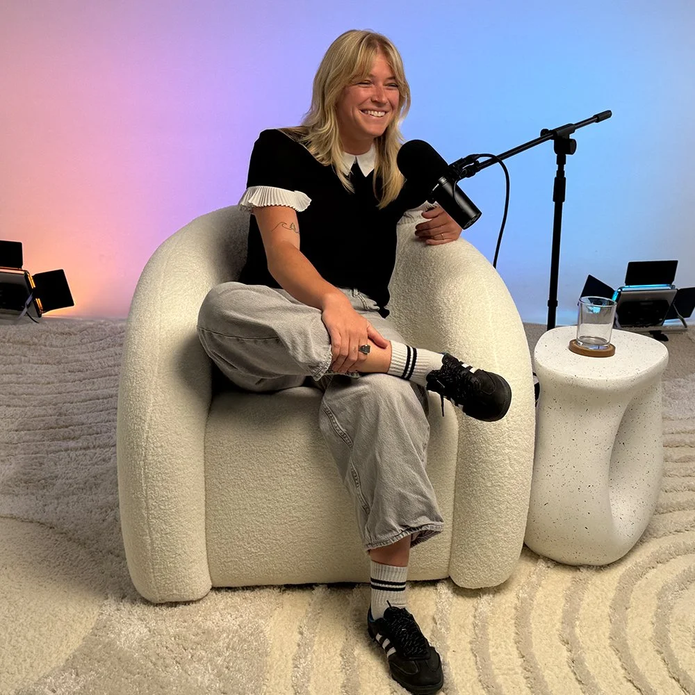 woman sitting on nice chair in podcast studio with microphone and lighting behind her
