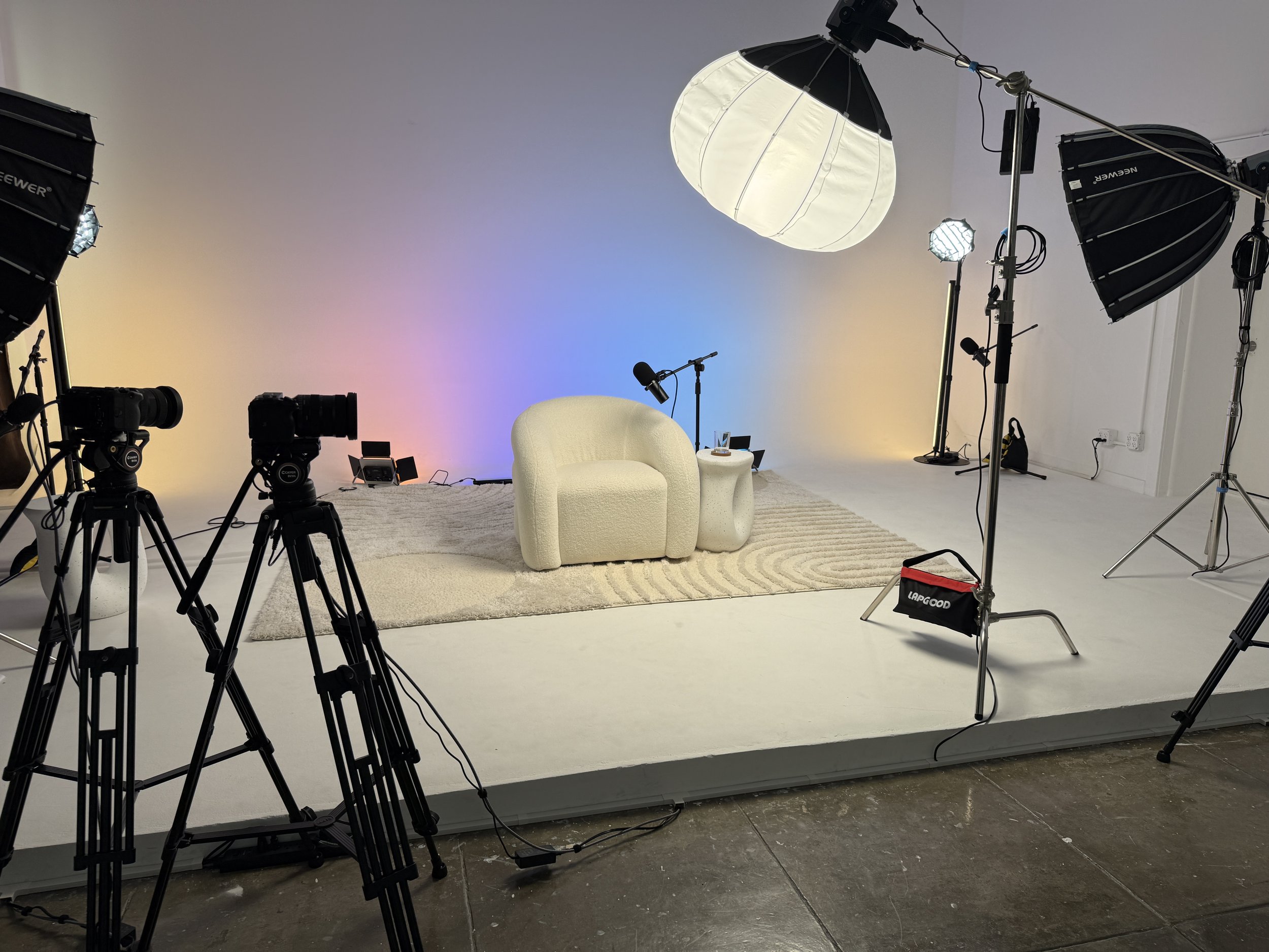 Behind-the-scenes view of a solo podcast setup surrounded by cameras and professional studio lights