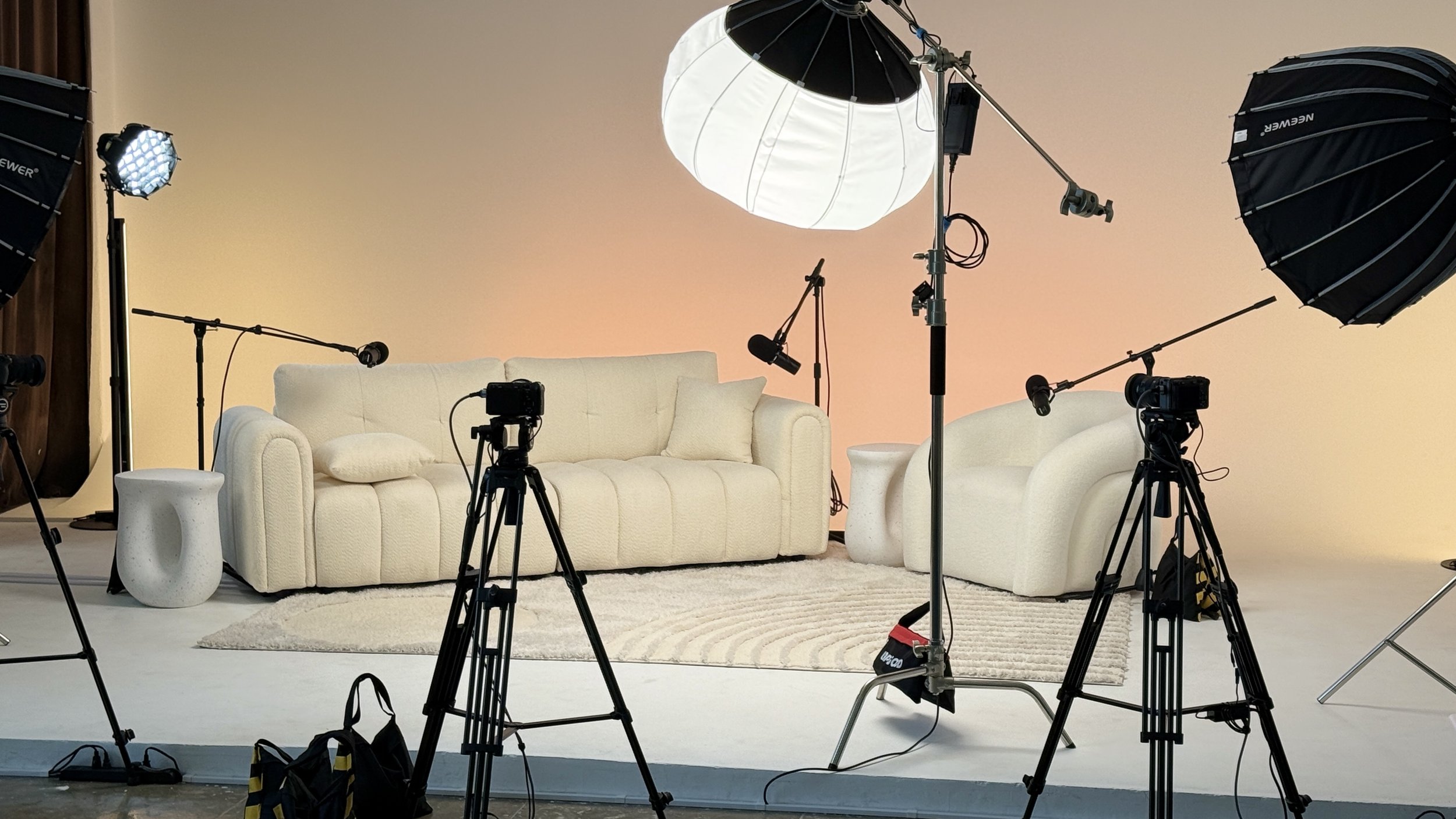 Wide view of Dari podcast studio with sofa, lounge chair, cameras, microphones, and production lighting