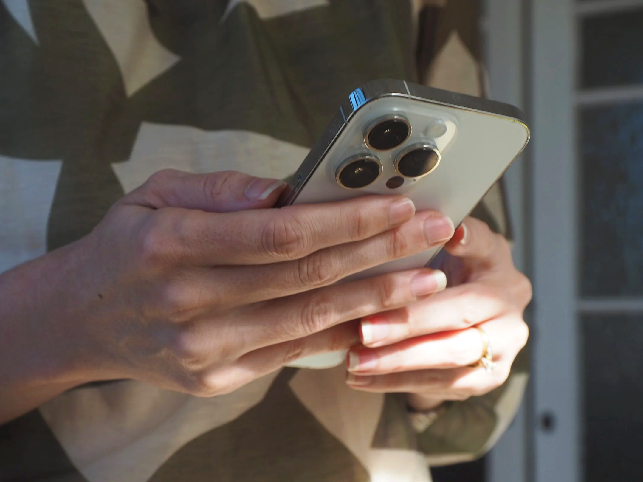 A person holding a smartphone with three wide-angle camera lenses on the back.