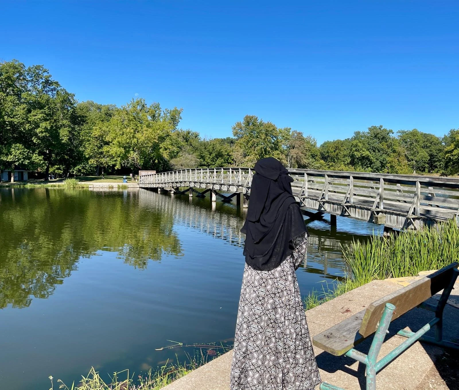 Muslim woman niqabi standing and looking at the water over a bridge