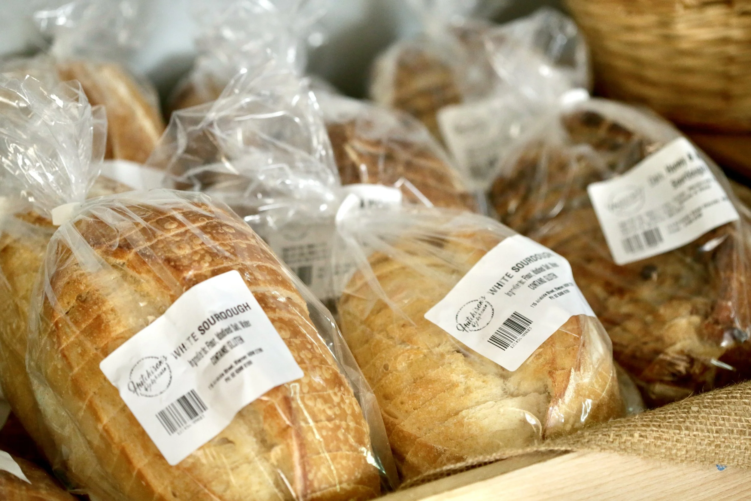 Loaves of bread in clear plastic bags on a wooden surface.