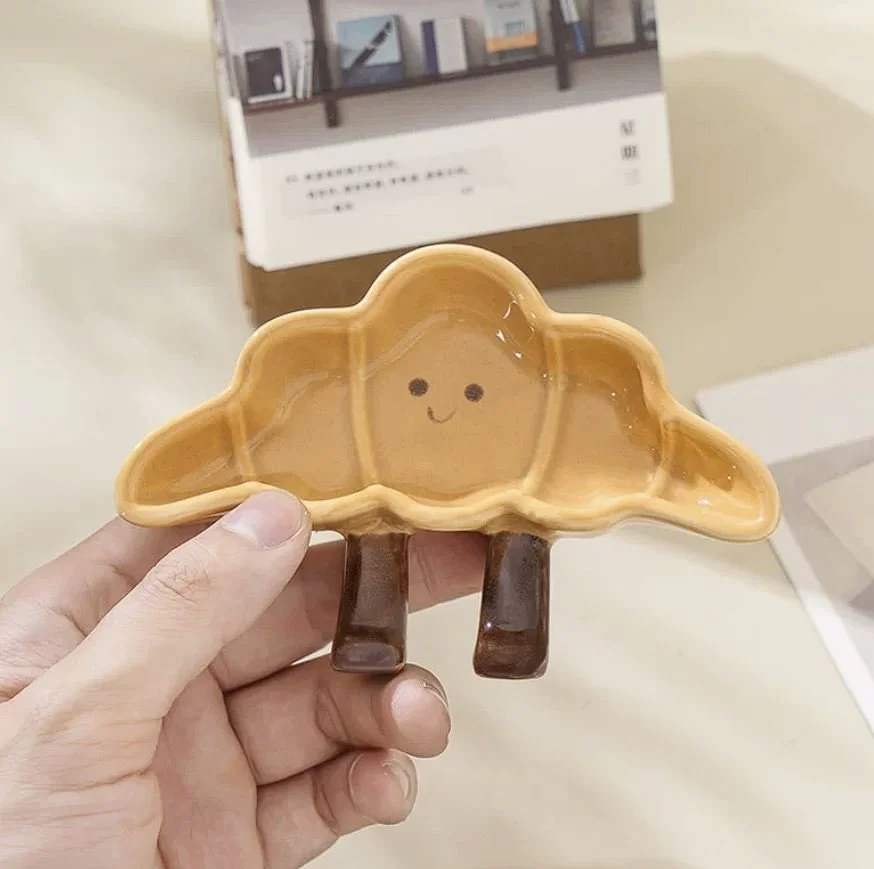 Cute croissant-shaped ceramic sauce plates with playful dangling legs, perfect for snacks, desserts, dipping sauces and cosy kawaii kitchen décor.