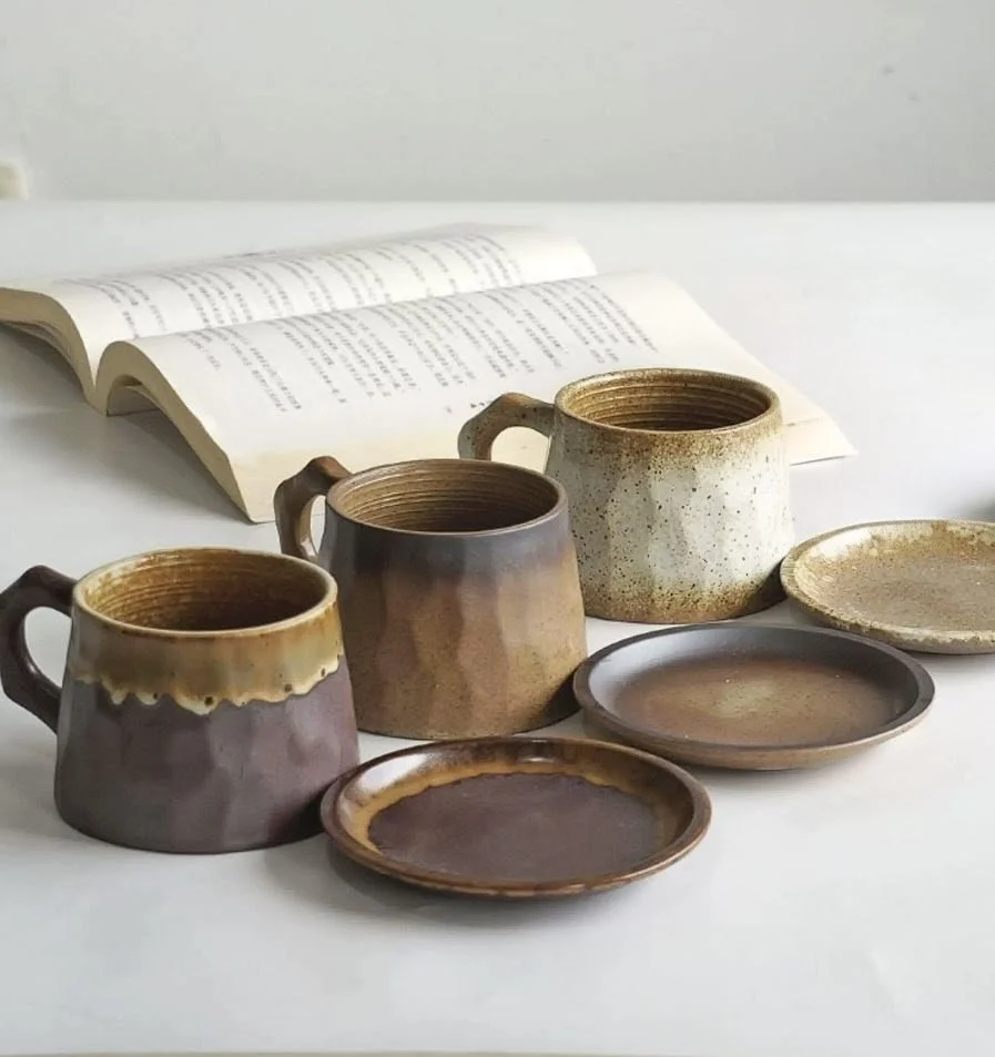 Rustic handmade ceramic mug set with earthy mountain-inspired glazes and matching saucers, perfect for cosy coffee rituals and minimalist home café décor.