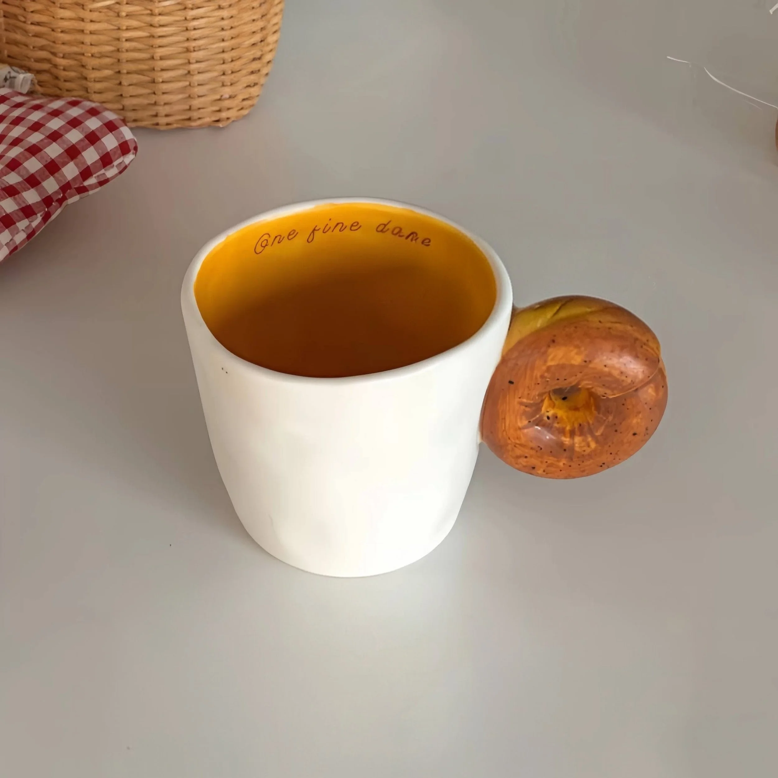 Cute ceramic mugs with croissant and bagel-shaped handles, featuring warm buttery tones and playful bakery-inspired design for cosy coffee moments.
