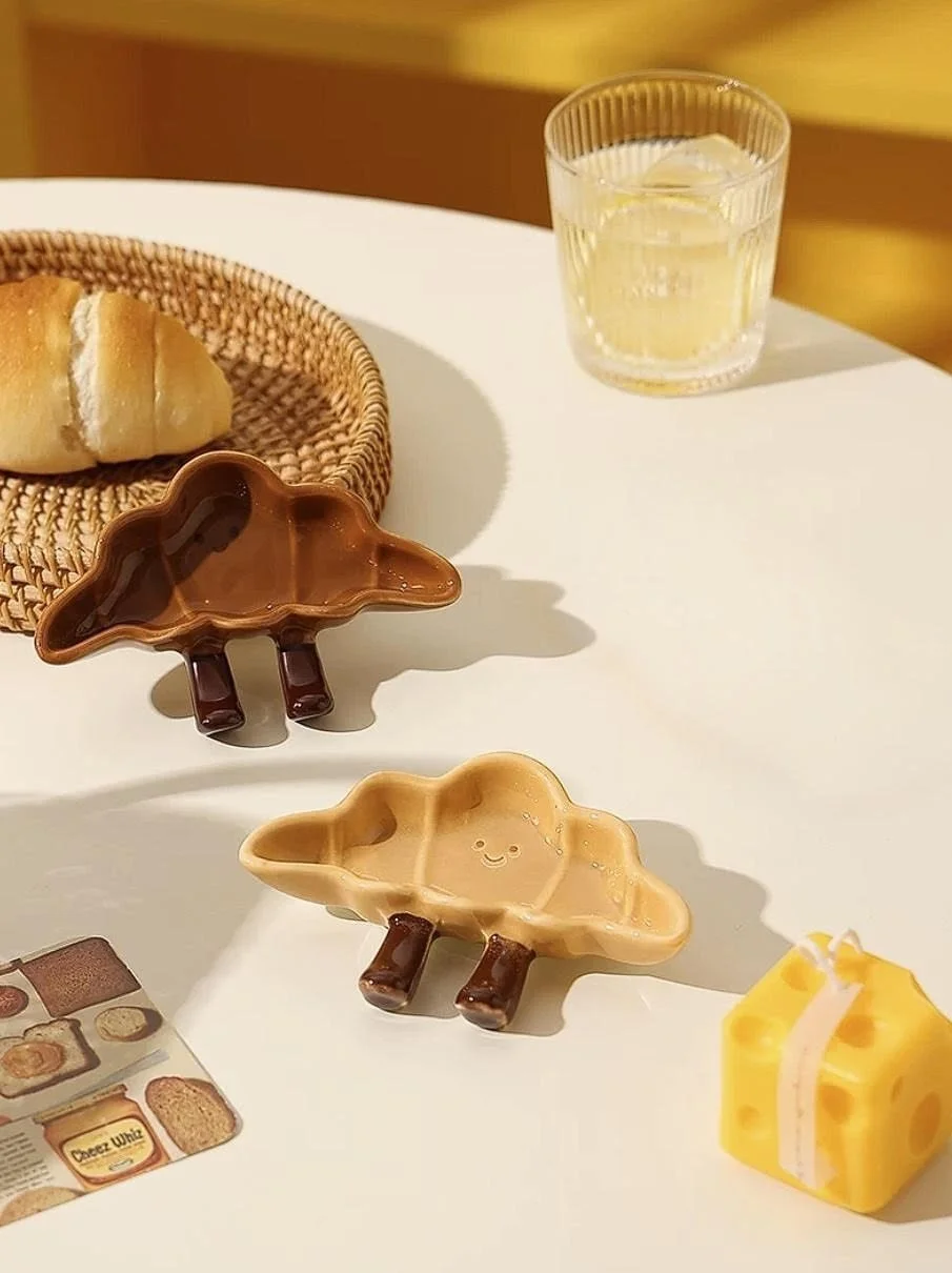 Cute croissant shaped ceramic snack plates with playful dangling legs, perfect for desserts, dipping sauces and cosy kawaii kitchen décor.