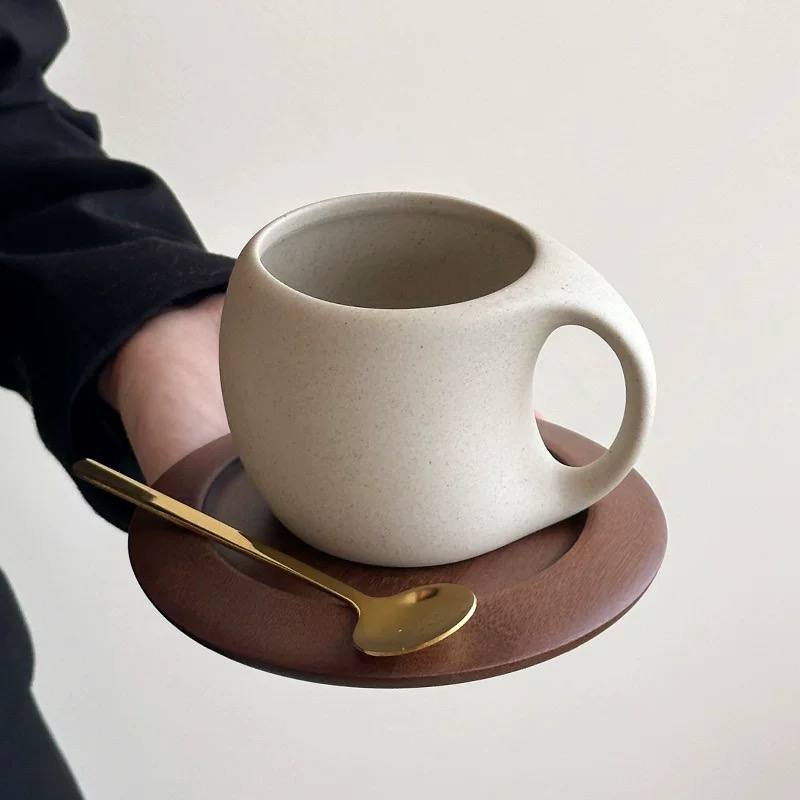 Minimalist ceramic latte mug with wooden saucer and gold spoon for cosy modern home café aesthetics.