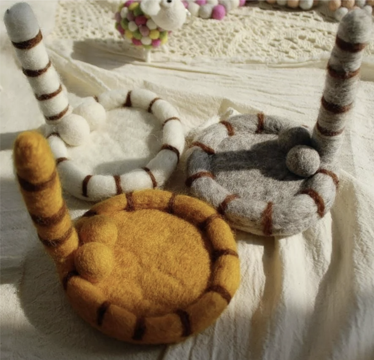 Cute handmade cat tail wool coaster with playful striped design, cosy felt texture and whimsical aesthetic for mugs, coffee cups and kawaii desk décor.
