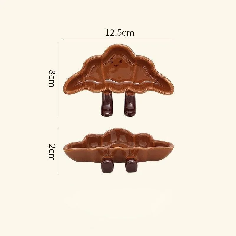 Cute croissant-shaped ceramic sauce plates with playful dangling legs, perfect for snacks, desserts, dipping sauces and cosy kawaii kitchen décor.