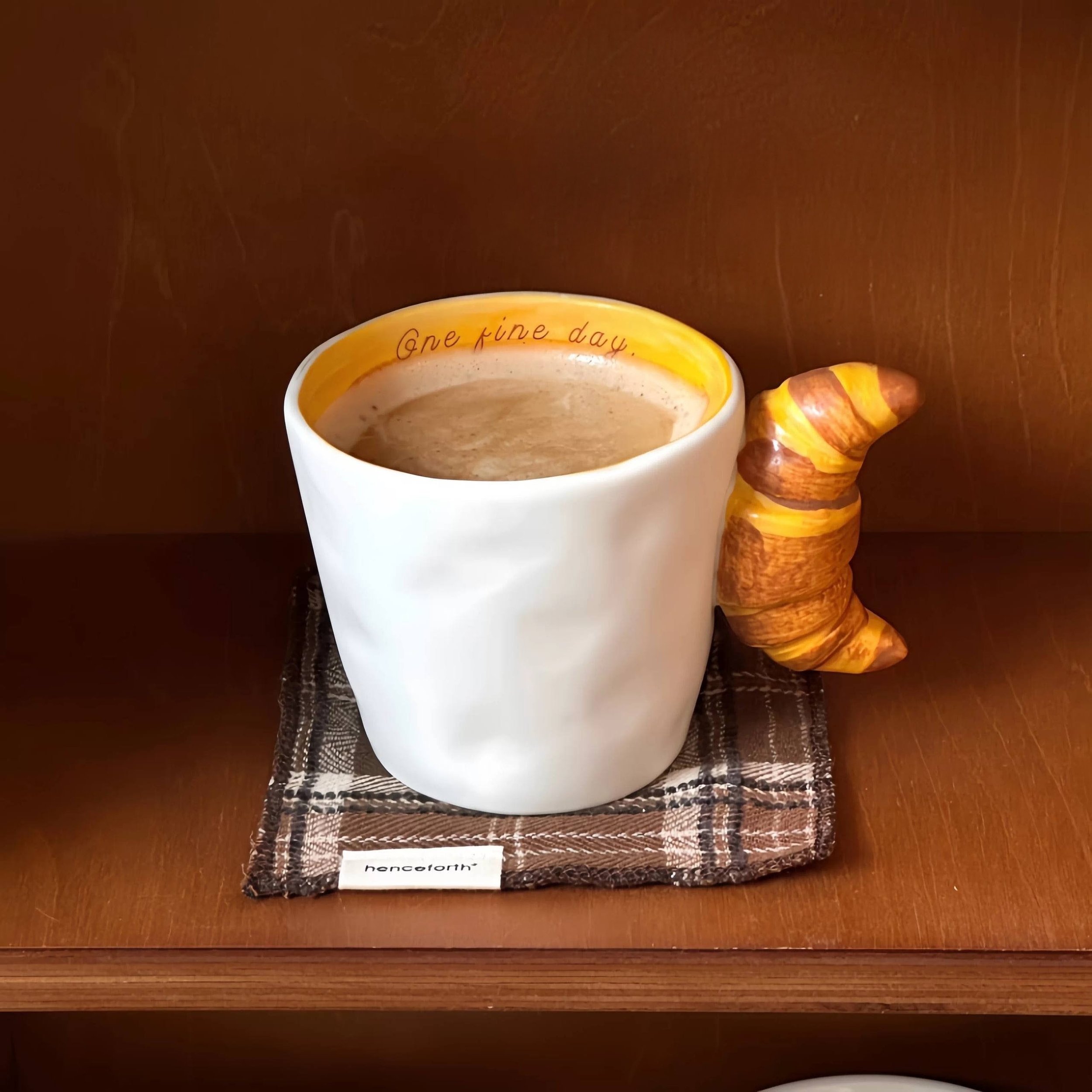 Cute ceramic mugs with croissant and bagel-shaped handles, featuring warm buttery tones and playful bakery-inspired design for cosy coffee moments.