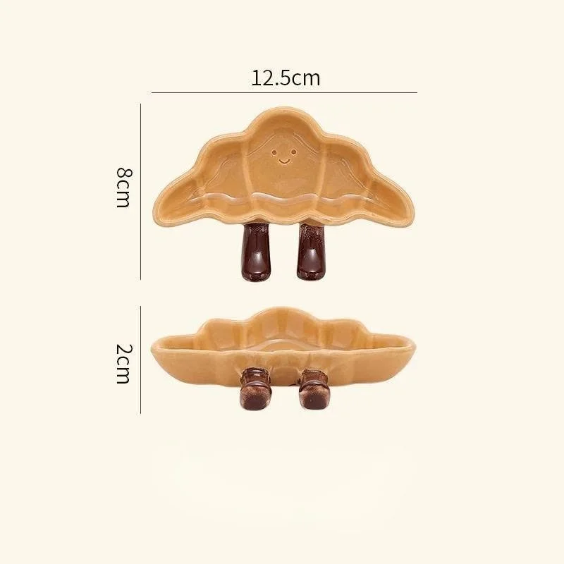 Cute croissant-shaped ceramic sauce plates with playful dangling legs, perfect for snacks, desserts, dipping sauces and cosy kawaii kitchen décor.