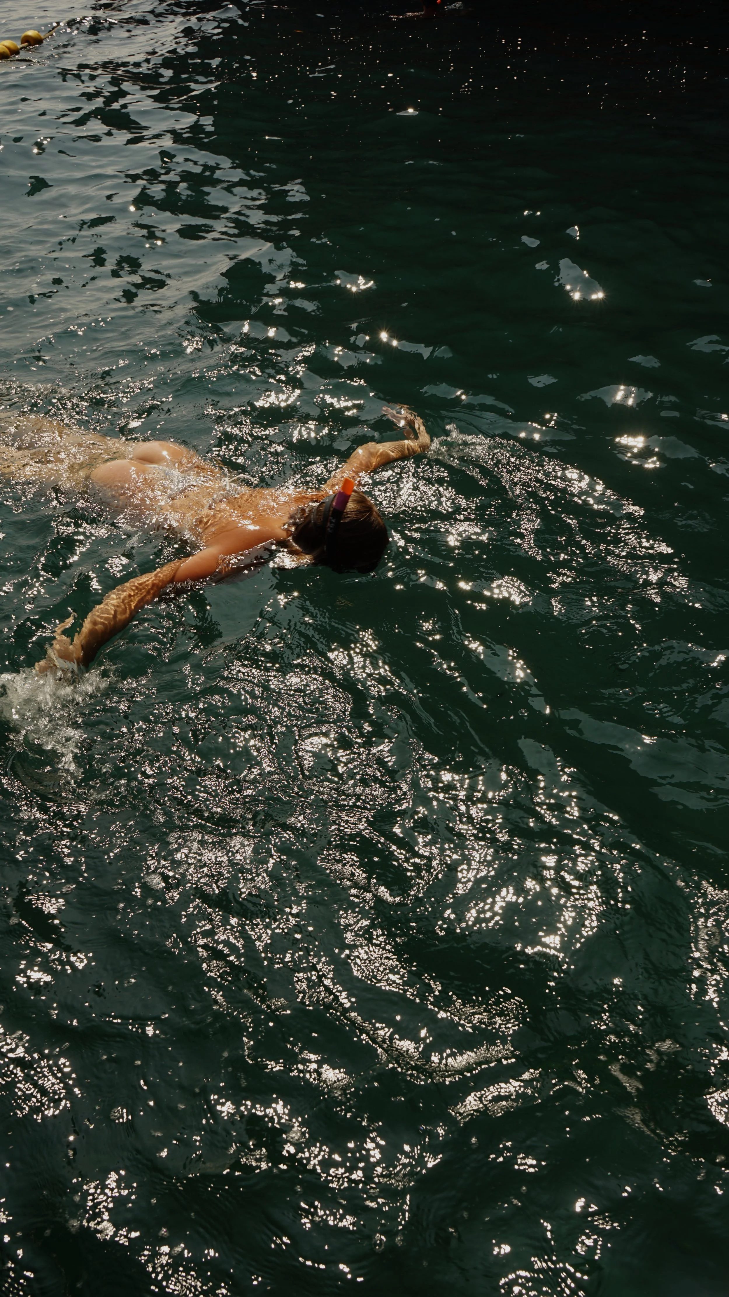 Person swimming in a body of water, wearing goggles and a snorkel.