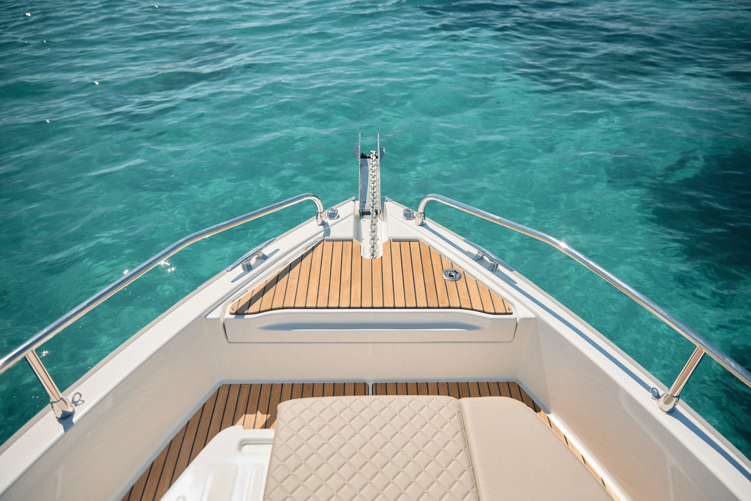 View from the bow of a boat showing turquoise water and a clear sky.