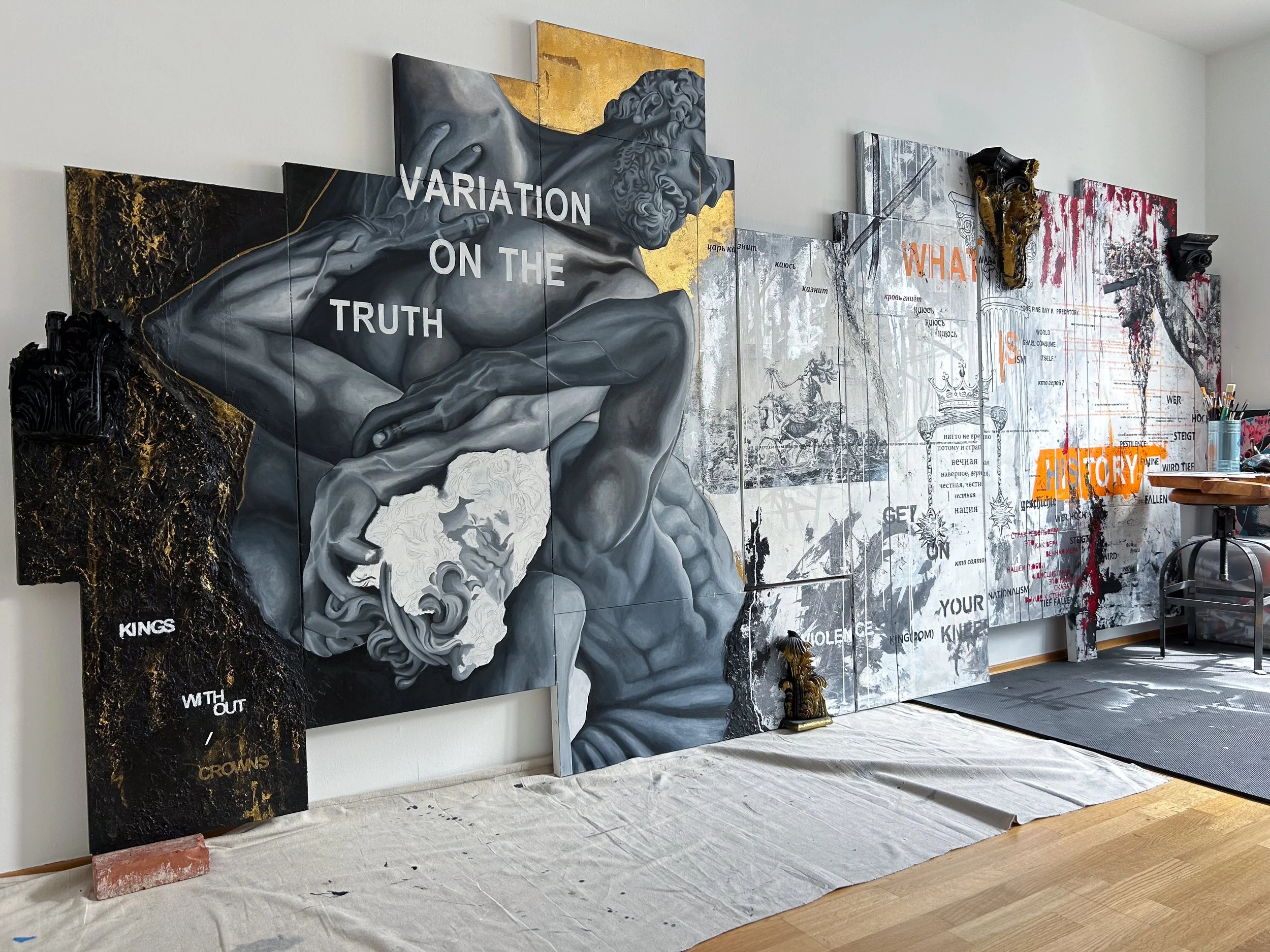 Display of mixed media artwork featuring classical sculpture and layered text elements on a wall.