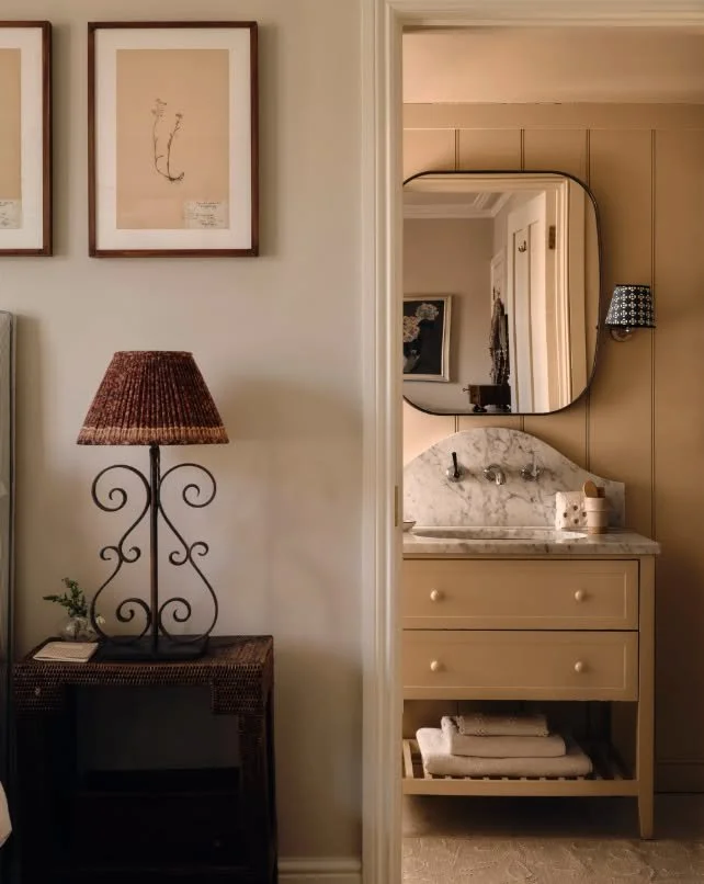 ''A view from the main bedroom into the en-suite bathroom, which is painted in pretty &lsquo;Lilac Pink&rsquo; by Edward Bulmer. A Loaf mirror is flanked by Pooky wall lights with Rosi de Ruig lampshades above the Carrara marble vanity unit.'' words 