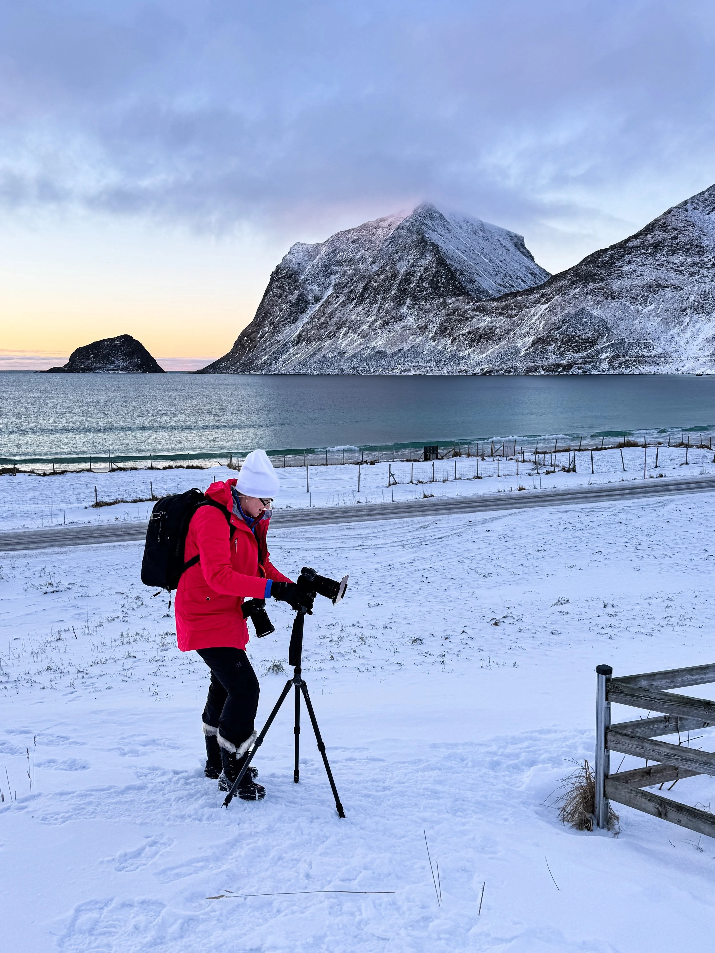 Photographer Linda Fox at work with Vik Beach, Lofoten Islands, Norway in the background.
