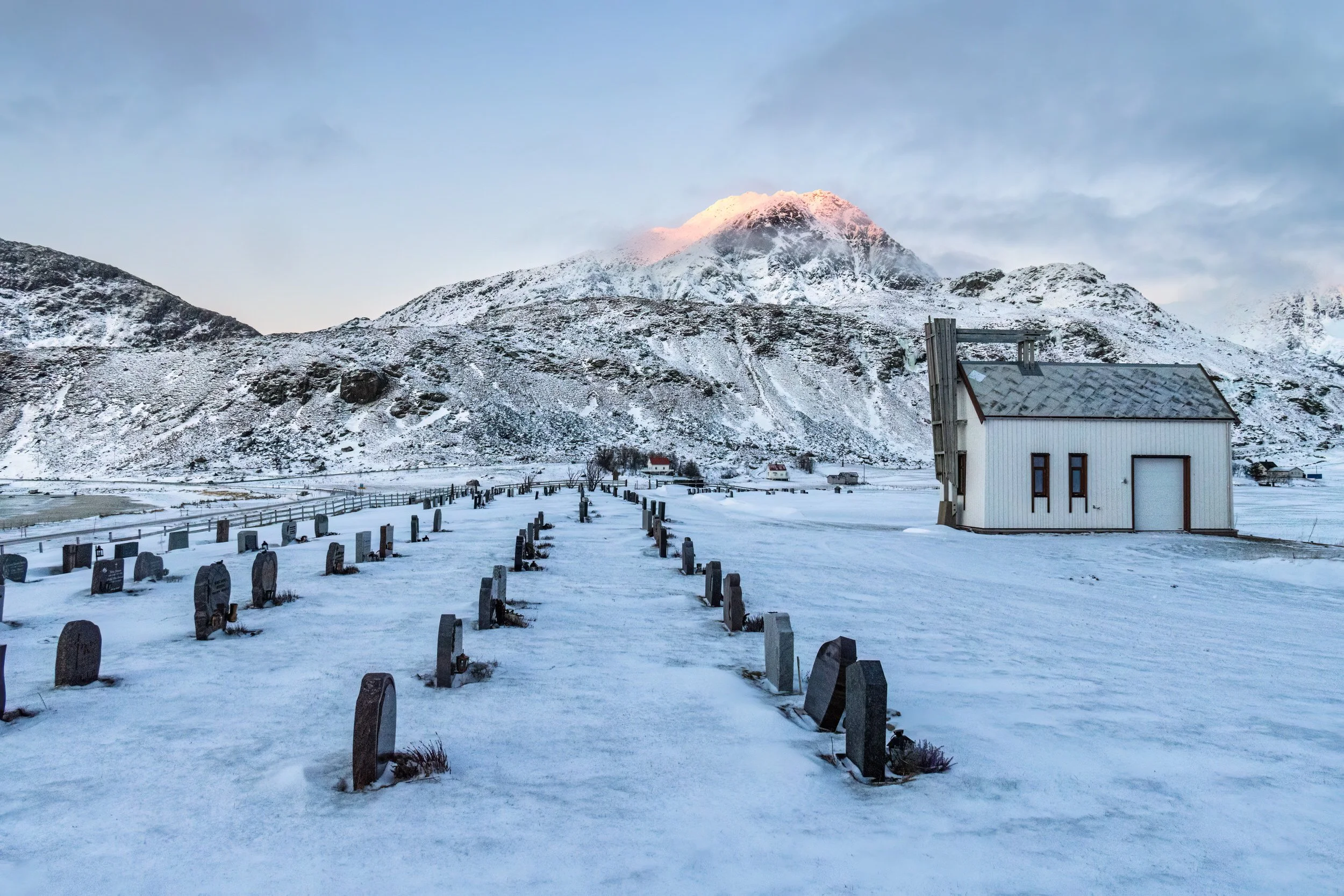Sun tipped mountains overlooking the church &amp; graveyard near Vik beach, Lofoten Islands, Norway.