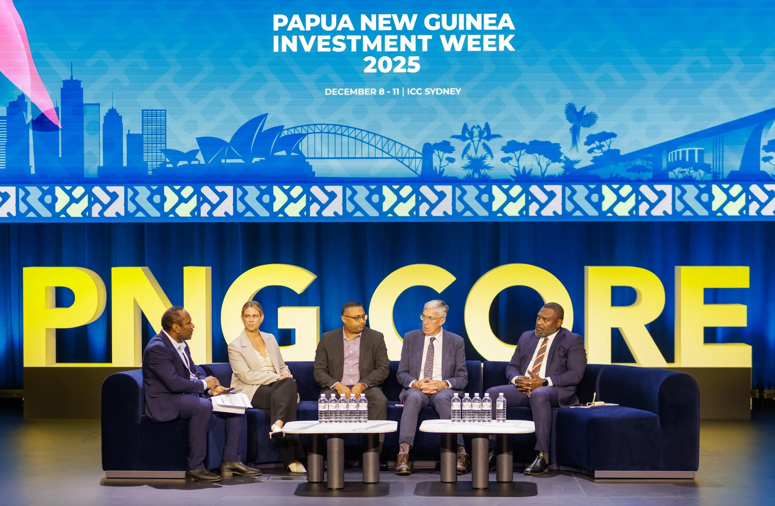 Panel discussion at Papua New Guinea Investment Week 2023 on December 8-11 at ICC Sydney, featuring five professionals seated on stage with a large sign that reads 'PNG GORE' behind them.