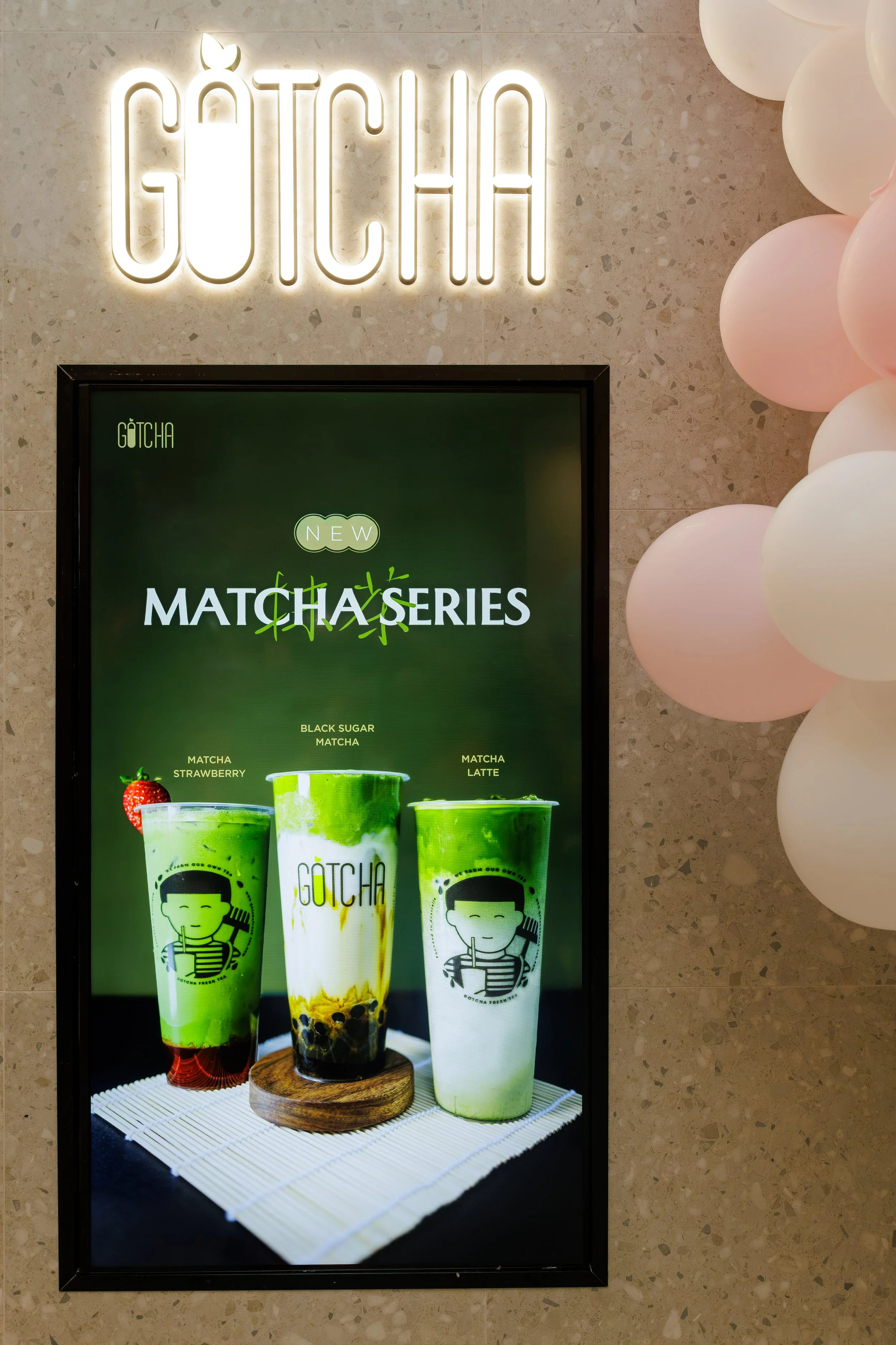 A digital display advertising matcha-flavored drinks, with images of three green beverages with straw characters, and a sign with the brand name 'GOTCHA' and flavor descriptions.