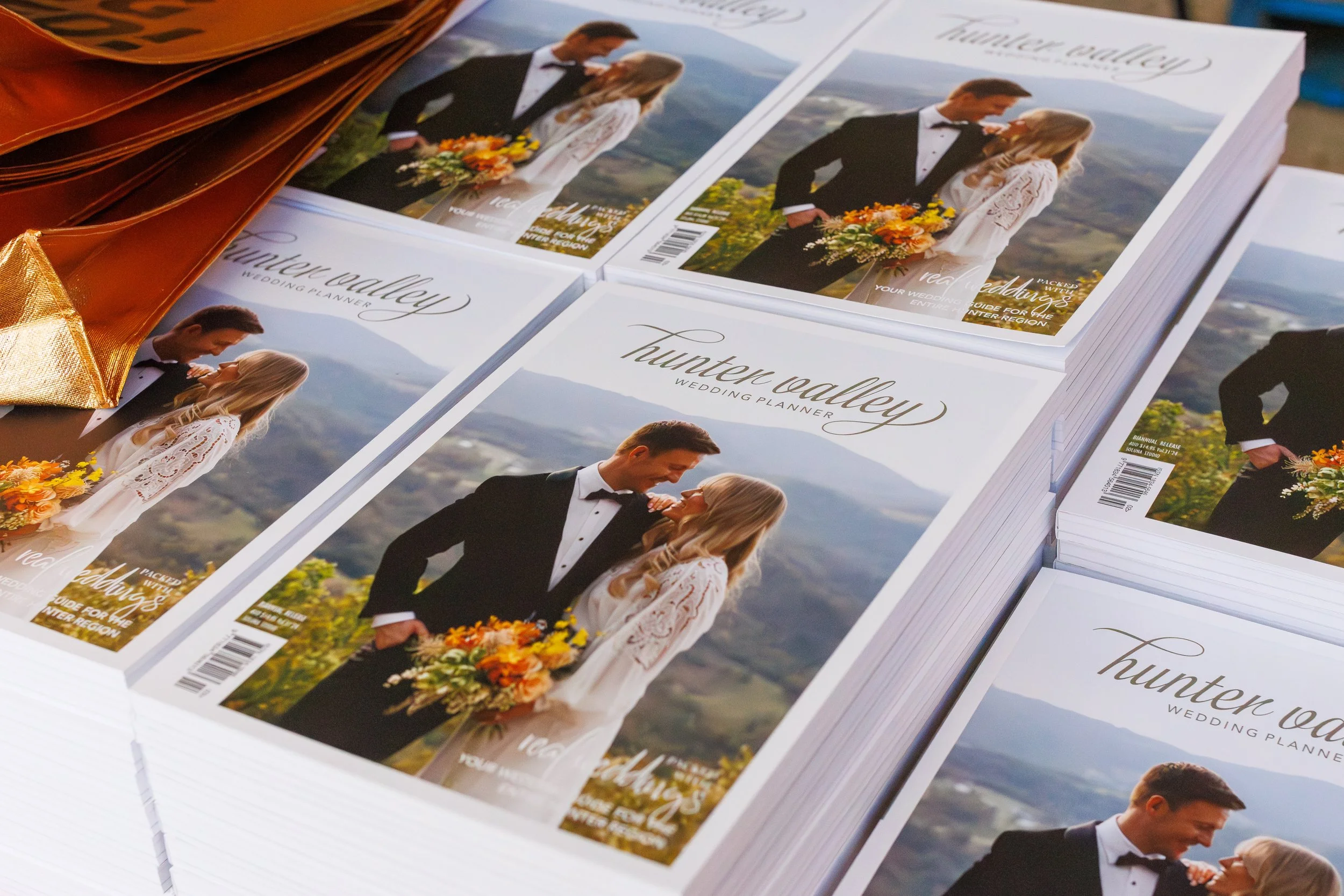 Stacks of wedding planning booklets with a cover photo of a bride and groom in outdoor setting