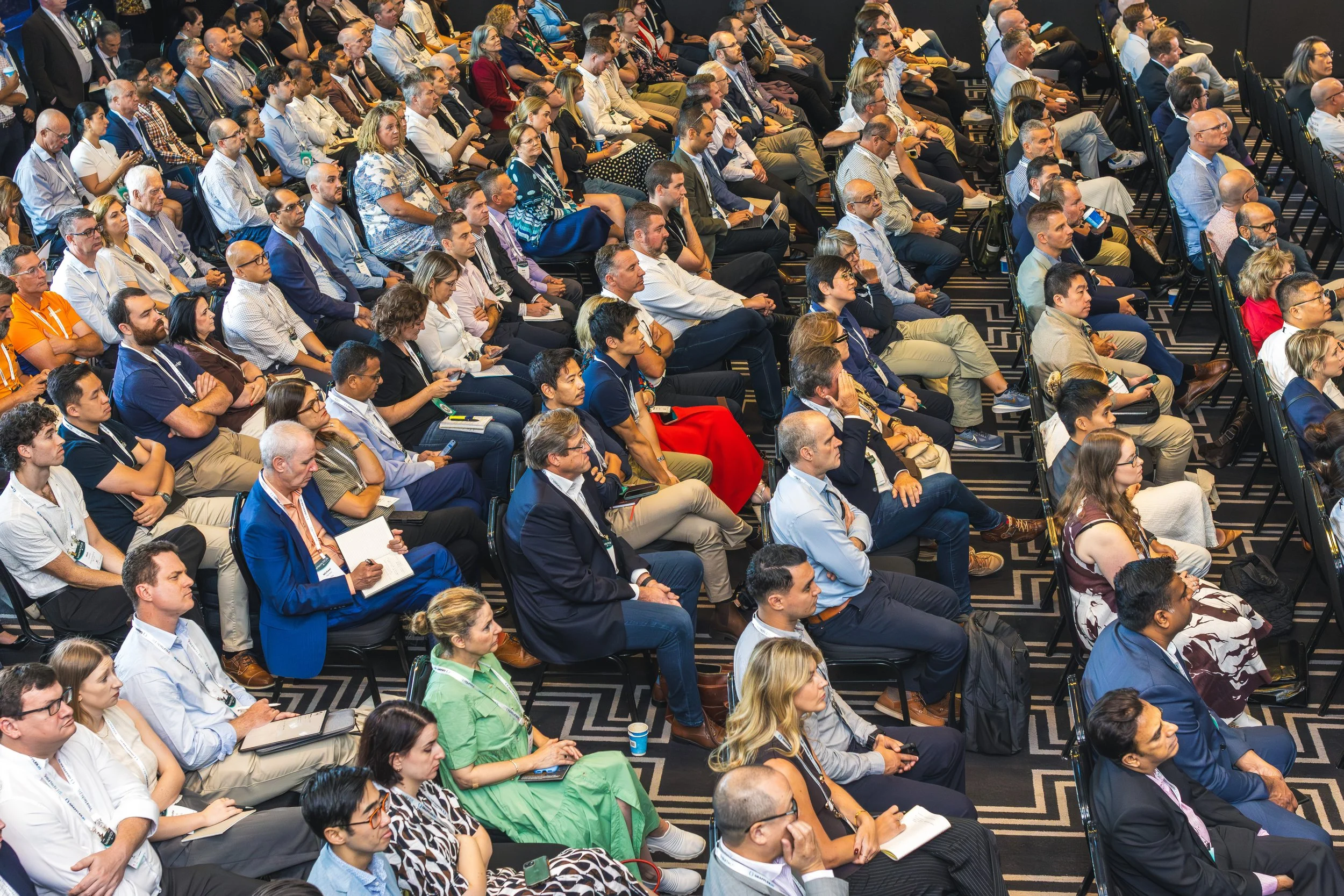 A large group of diverse people seated in rows attending a conference or seminar.