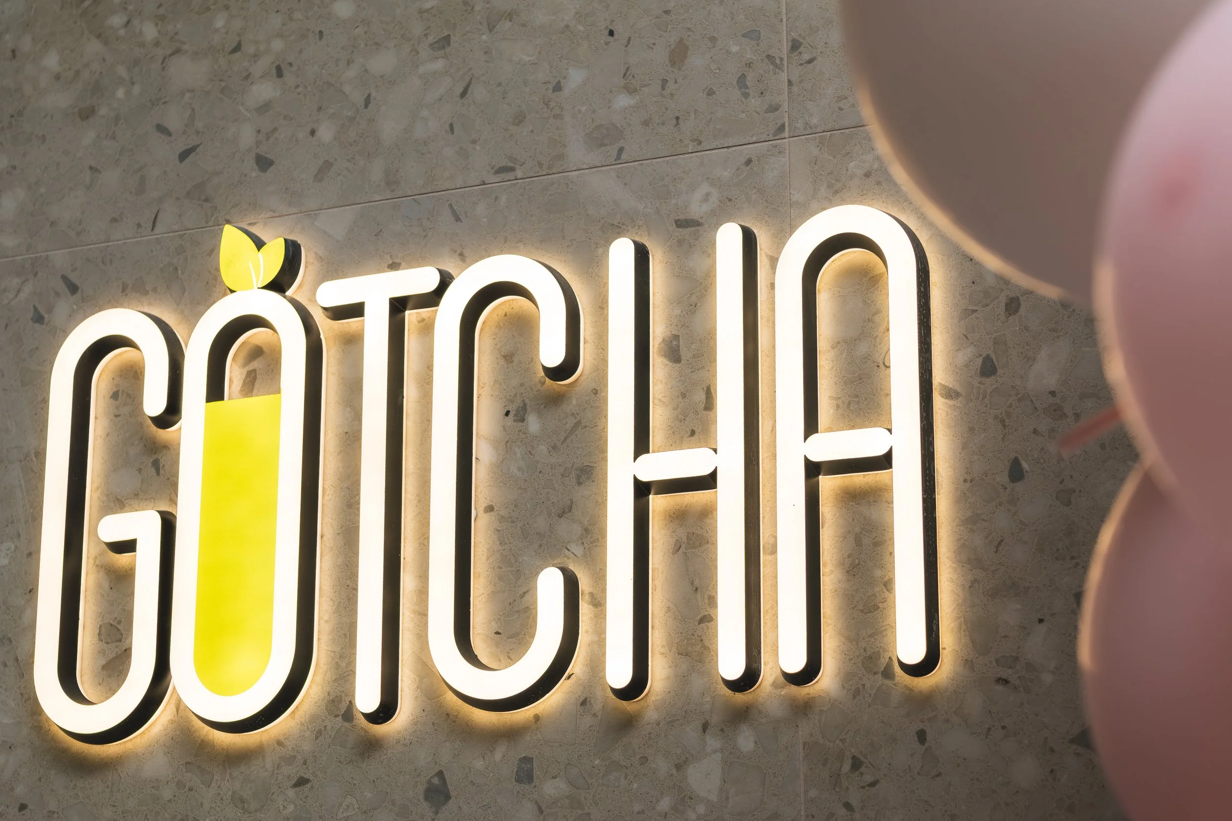 Illuminated sign with the word 'moth' on a speckled stone wall. Part of a pink object is visible on the right side.