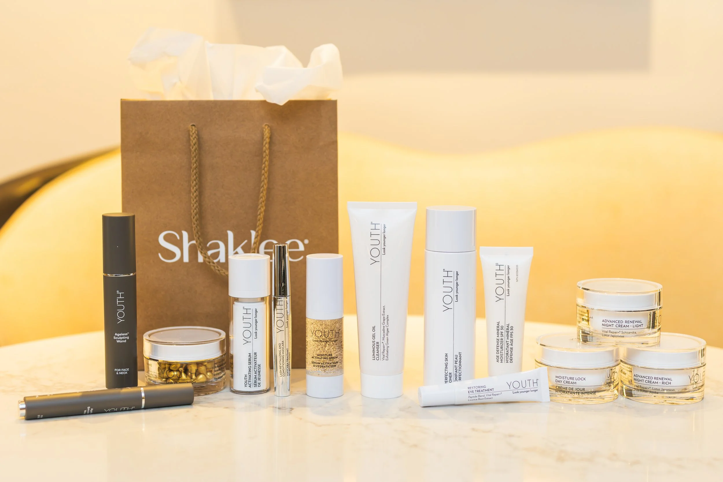 Collection of skincare and beauty products including tubes, jars, and bottles arranged on a surface with a shopping bag in the background.