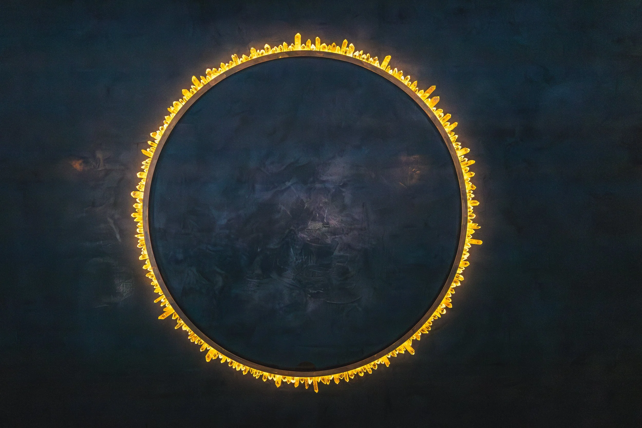 A circular mirror with a decorative yellow light border, mounted on a dark wall.