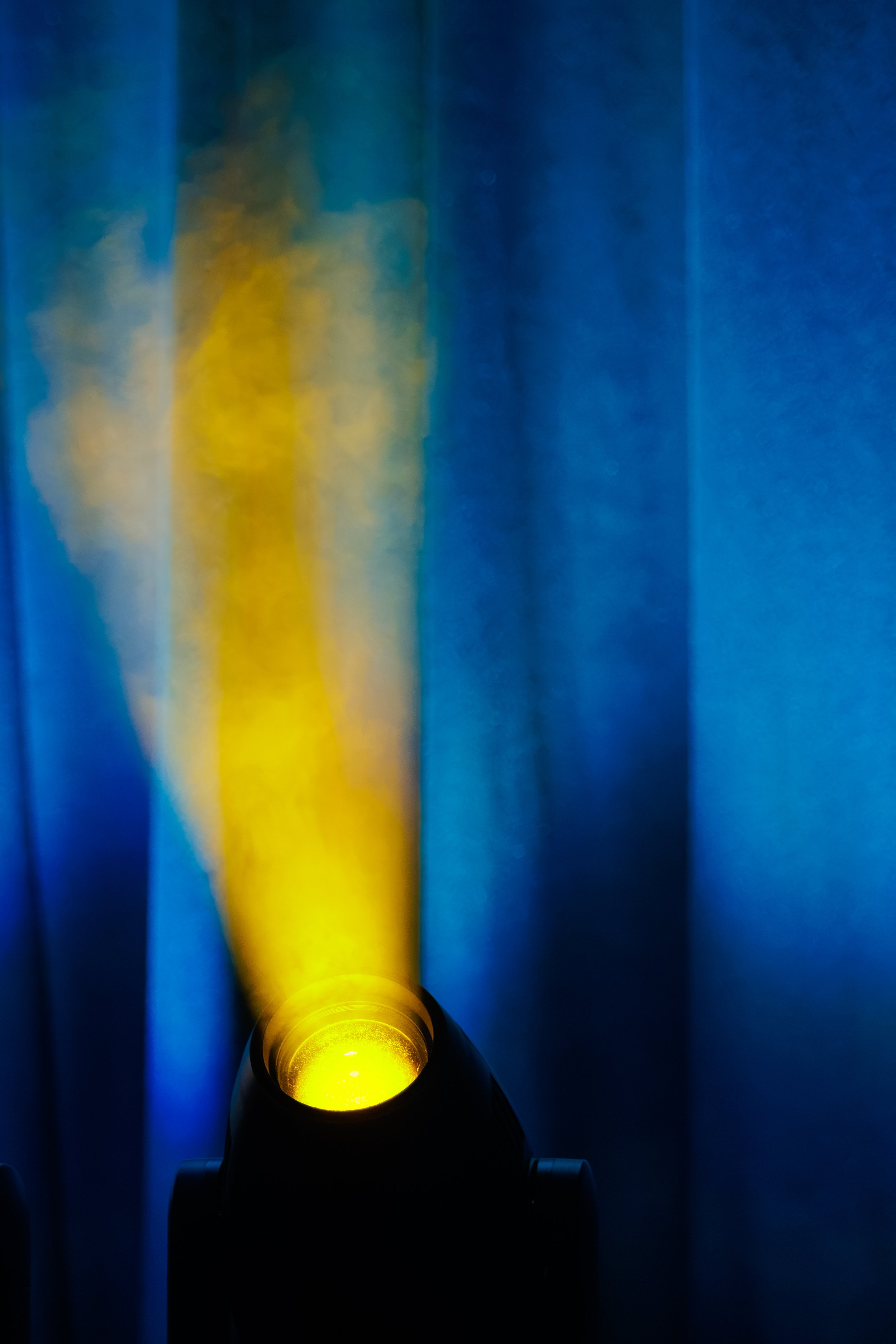 A flashlight shining a yellow beam on a blue background.