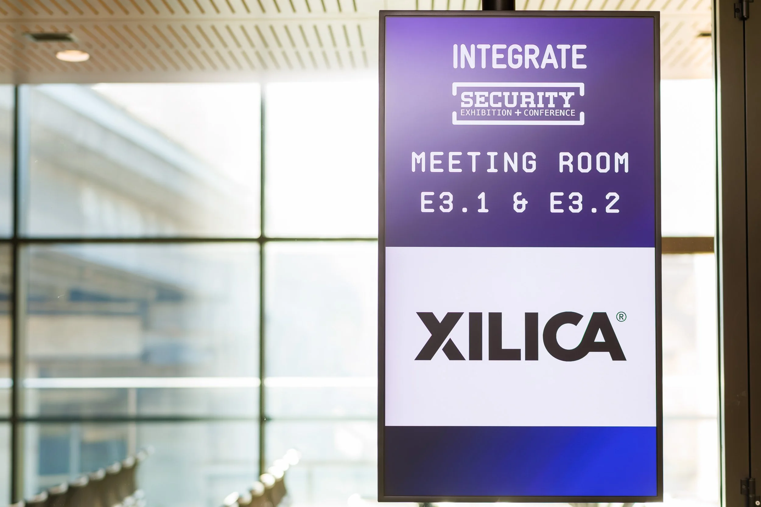 Digital sign in a meeting room indicating an integrated security exhibition and conference, with room numbers E3.1 and E3.2.