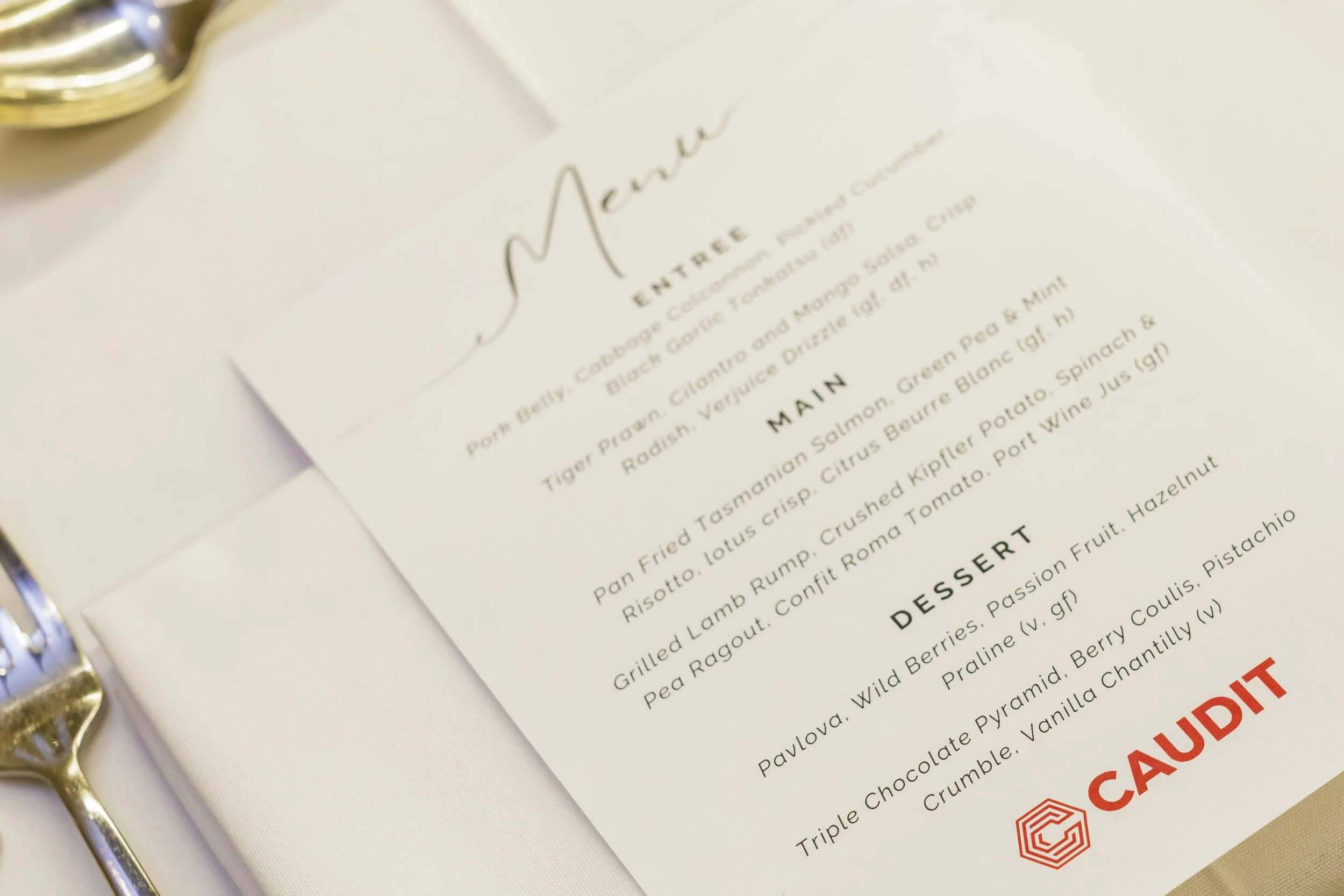 Close-up of a printed menu with a silver clip on the top left corner, featuring a list of food items and descriptions.