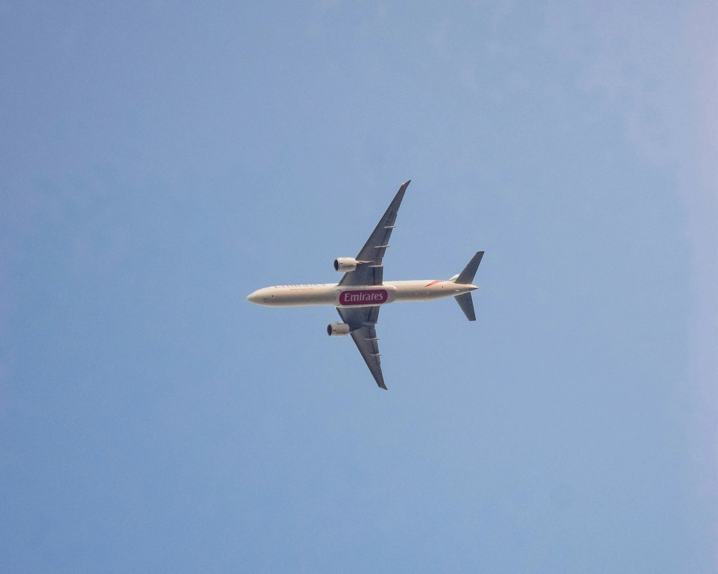 An airplane in flight against a blue sky with some clouds.